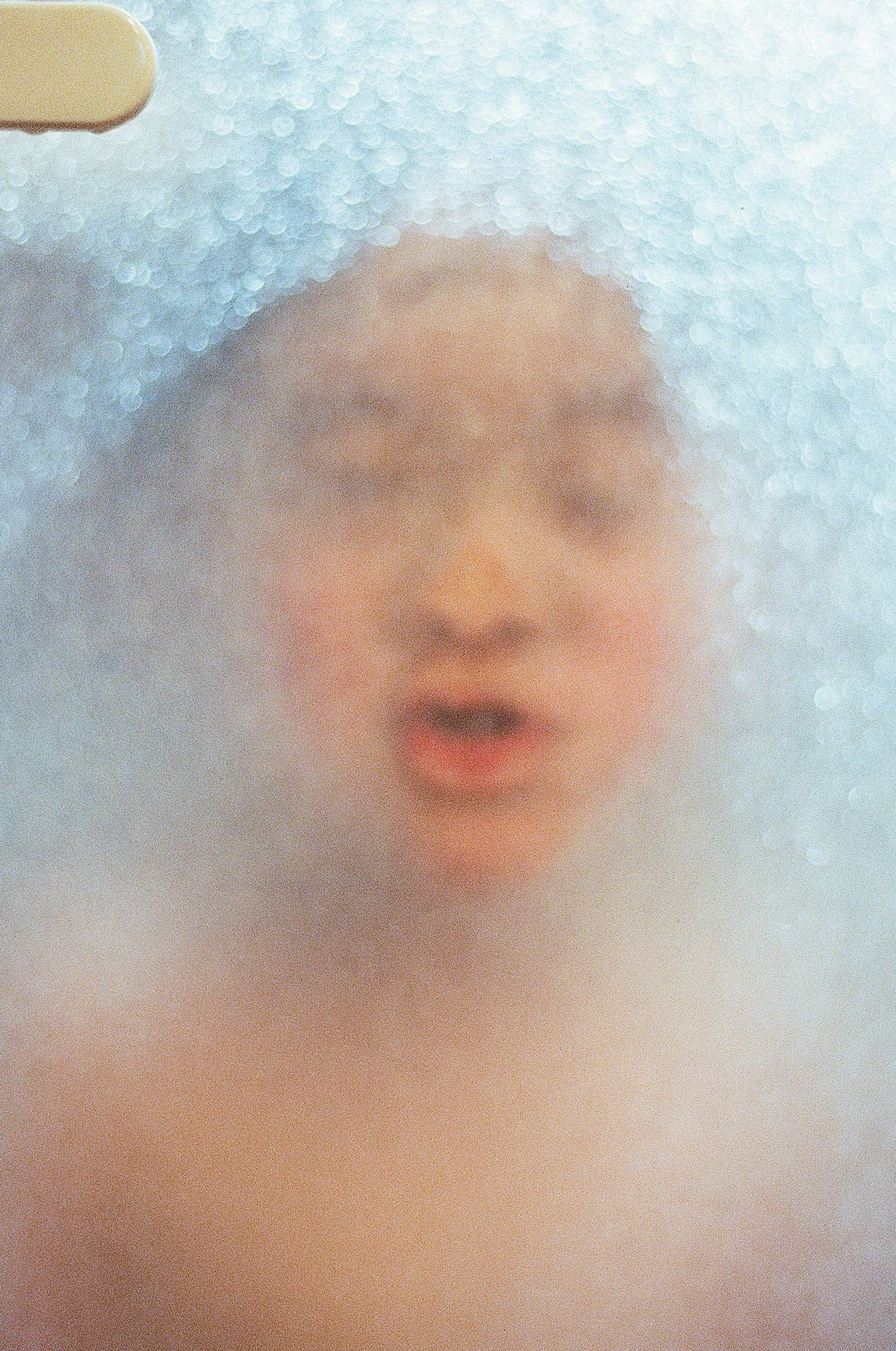 A child's face and expression seen through a foggy glass