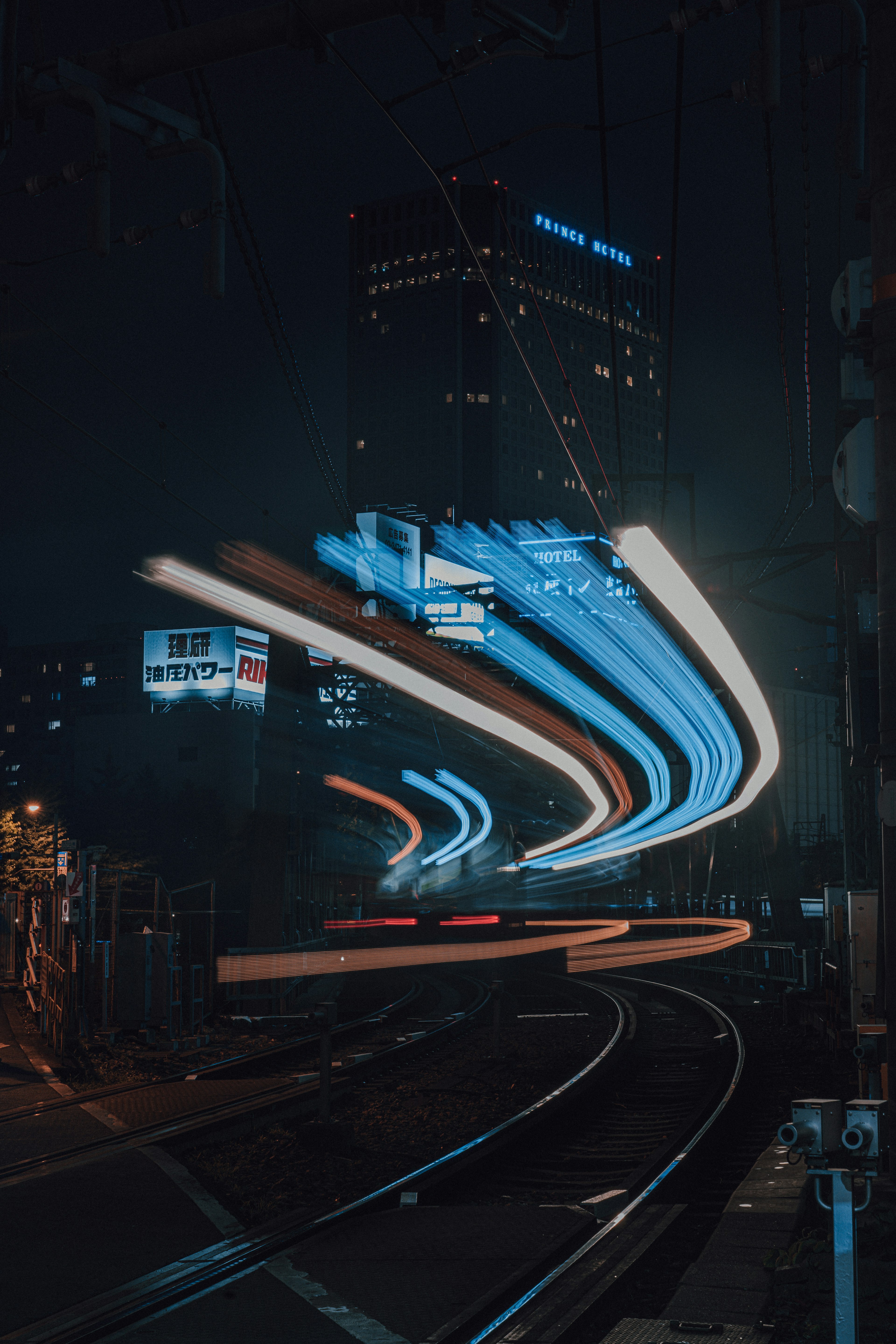 Paesaggio urbano notturno con binari del treno e luci brillanti