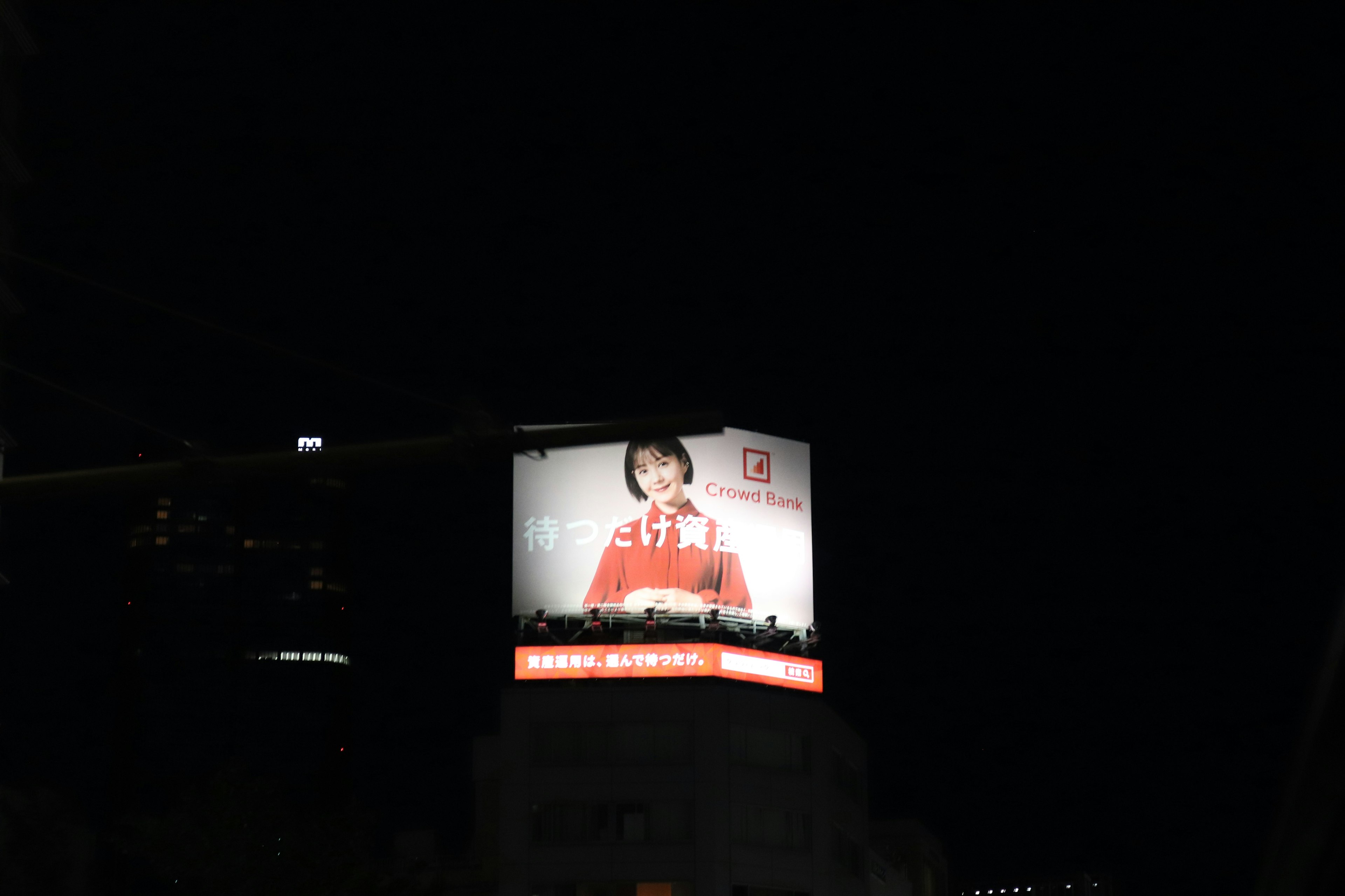 Large advertisement billboard featuring a woman in a red outfit at night