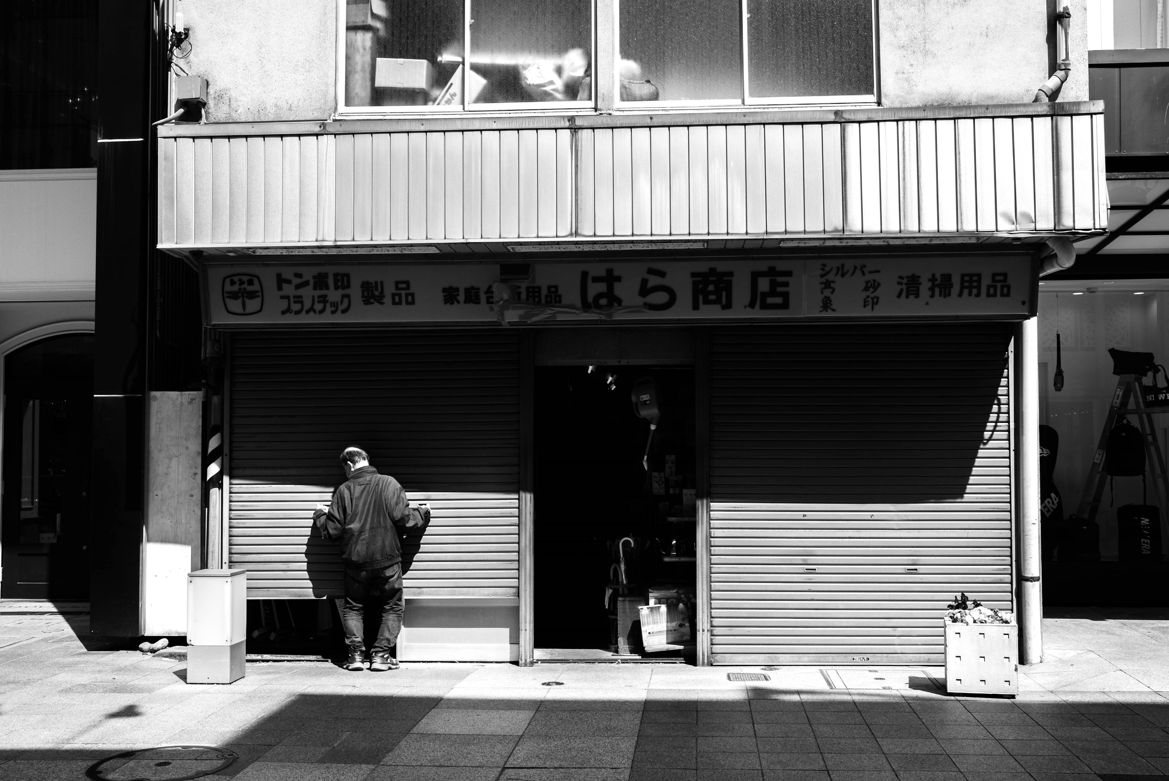 Foto en blanco y negro de la fachada de una tienda con una persona