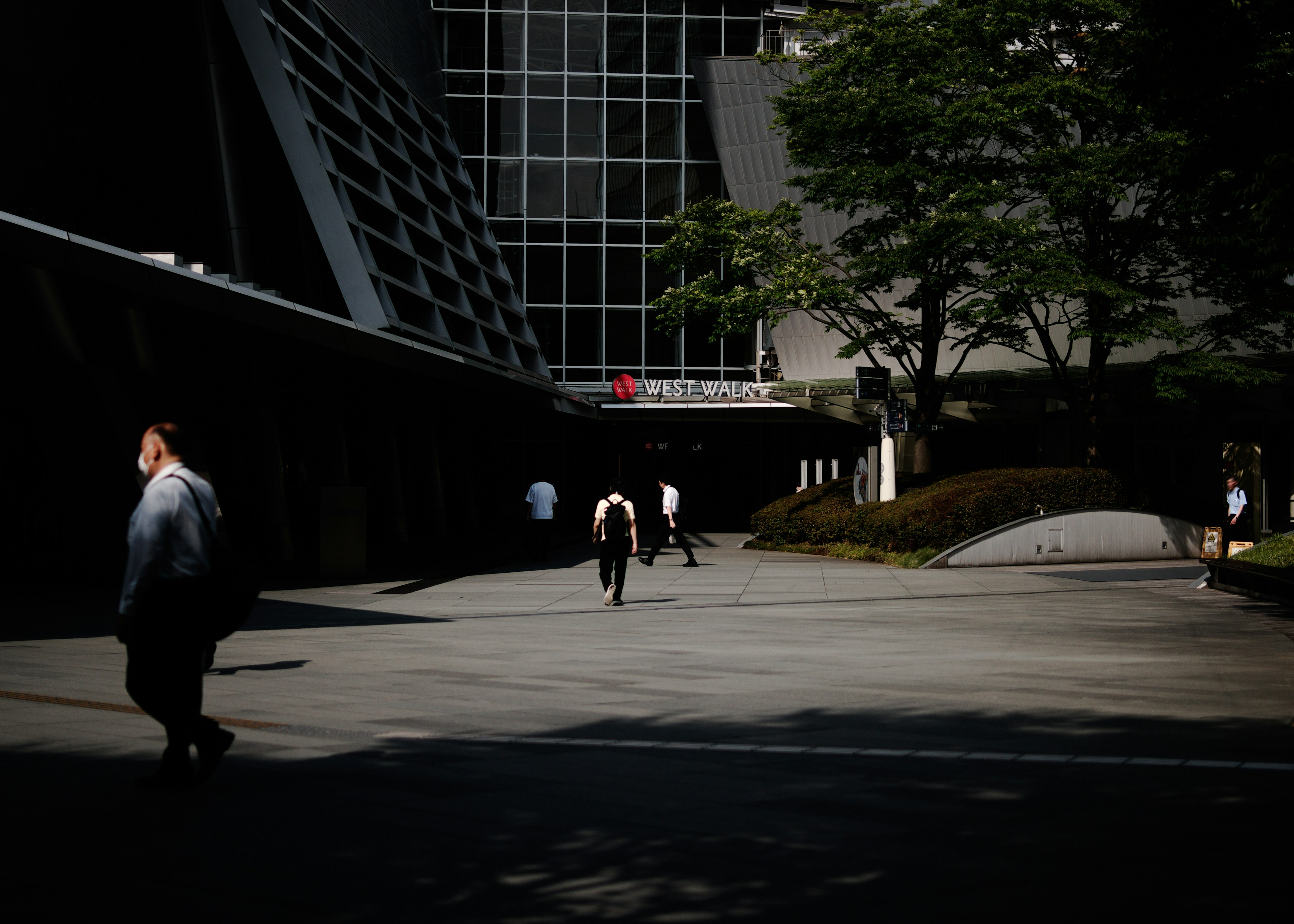 Scène urbaine avec des personnes marchant et des ombres contrastantes