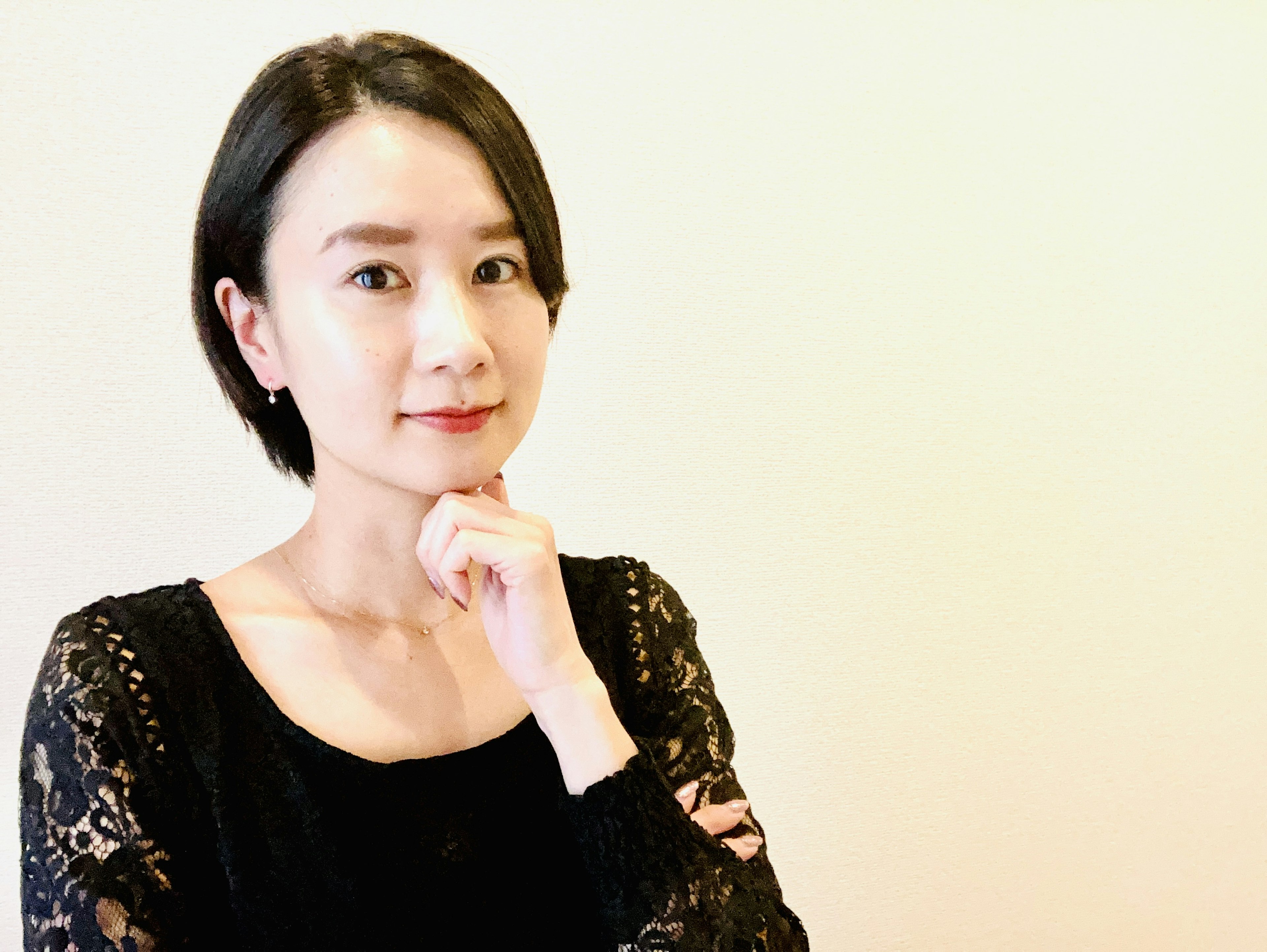 Woman in black lace top with short hair posing thoughtfully