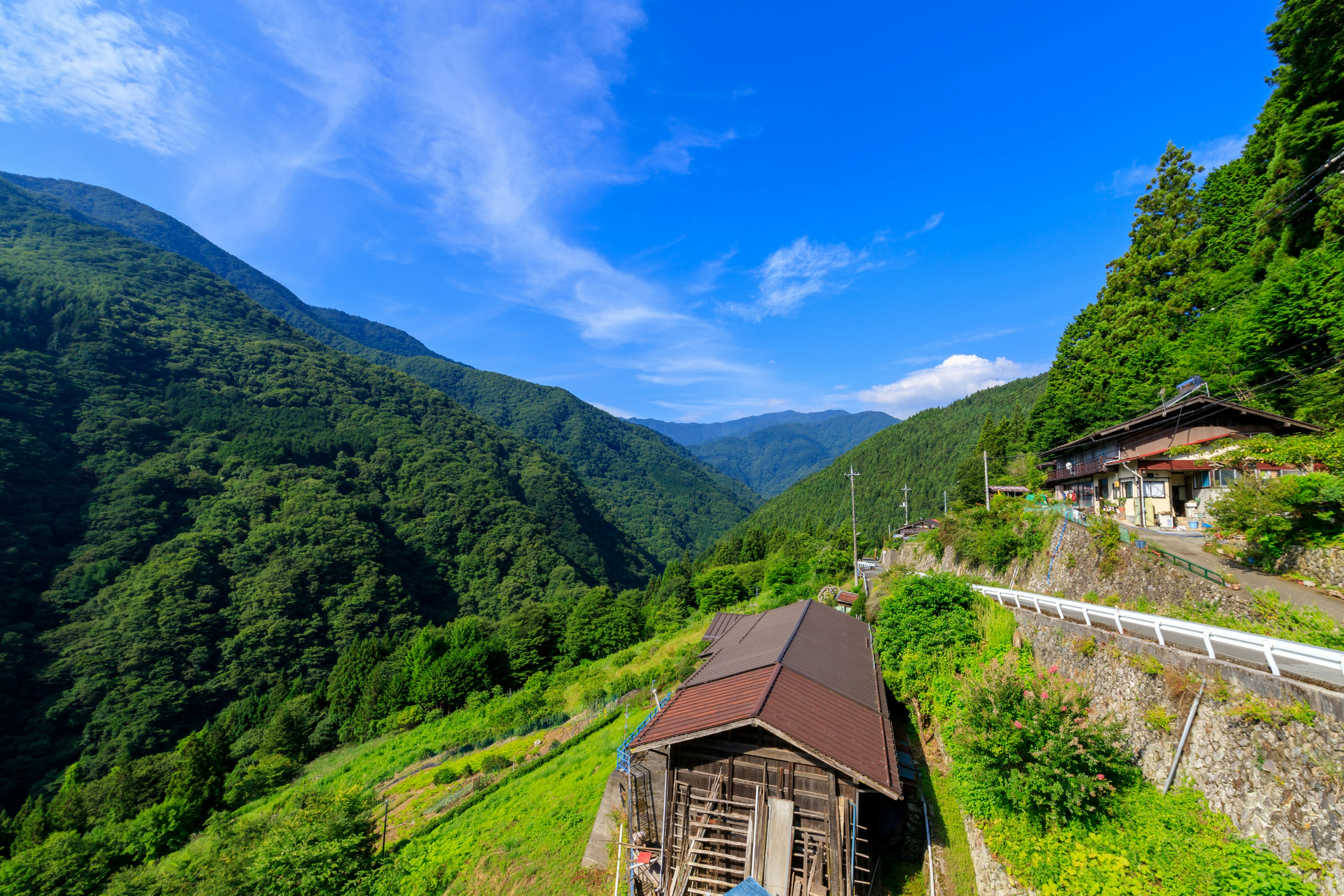 Vecchio edificio in legno circondato da montagne lussureggianti e cielo blu