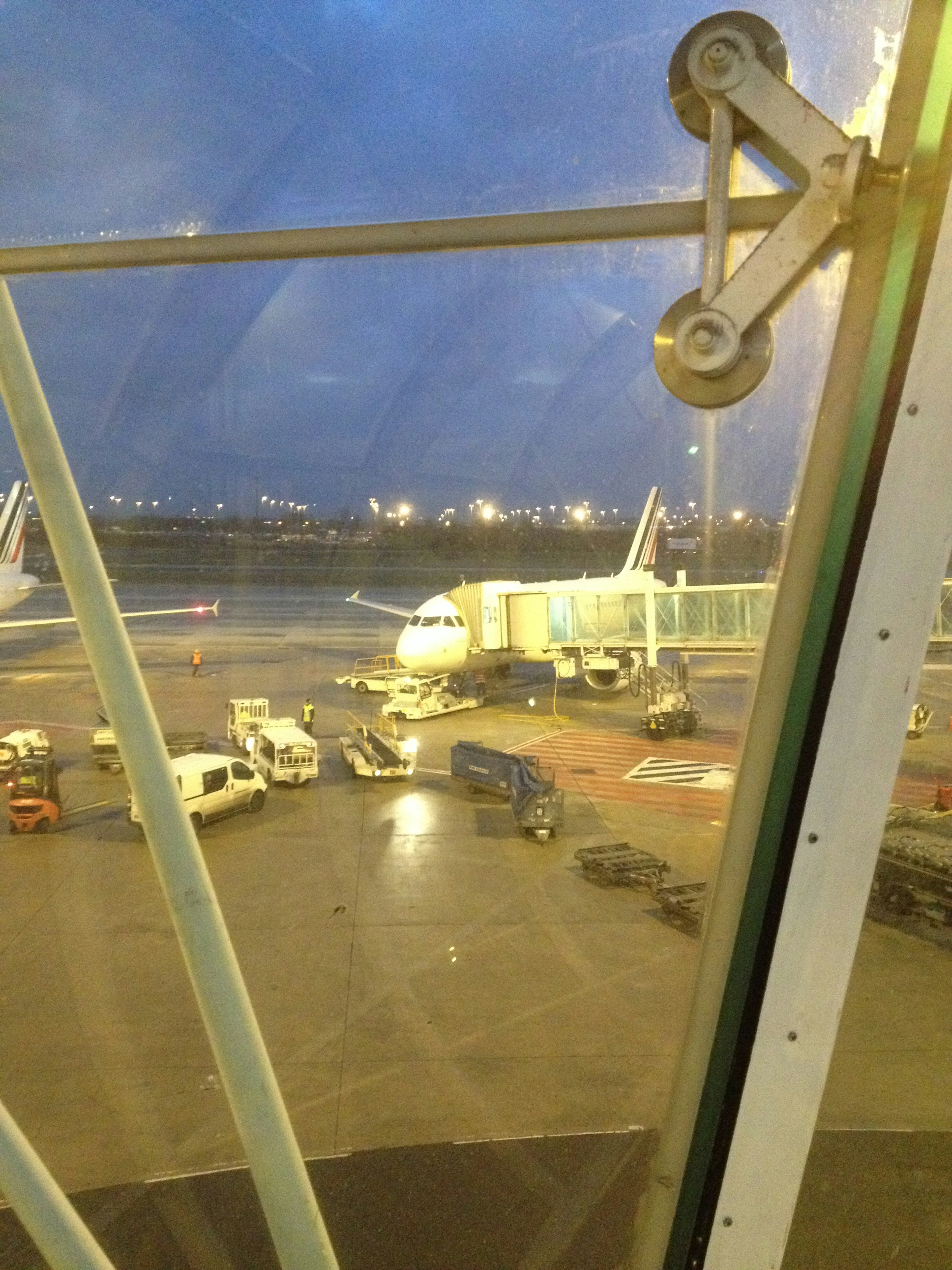 Vue nocturne depuis la fenêtre de l'aéroport montrant un avion et des véhicules de service au sol