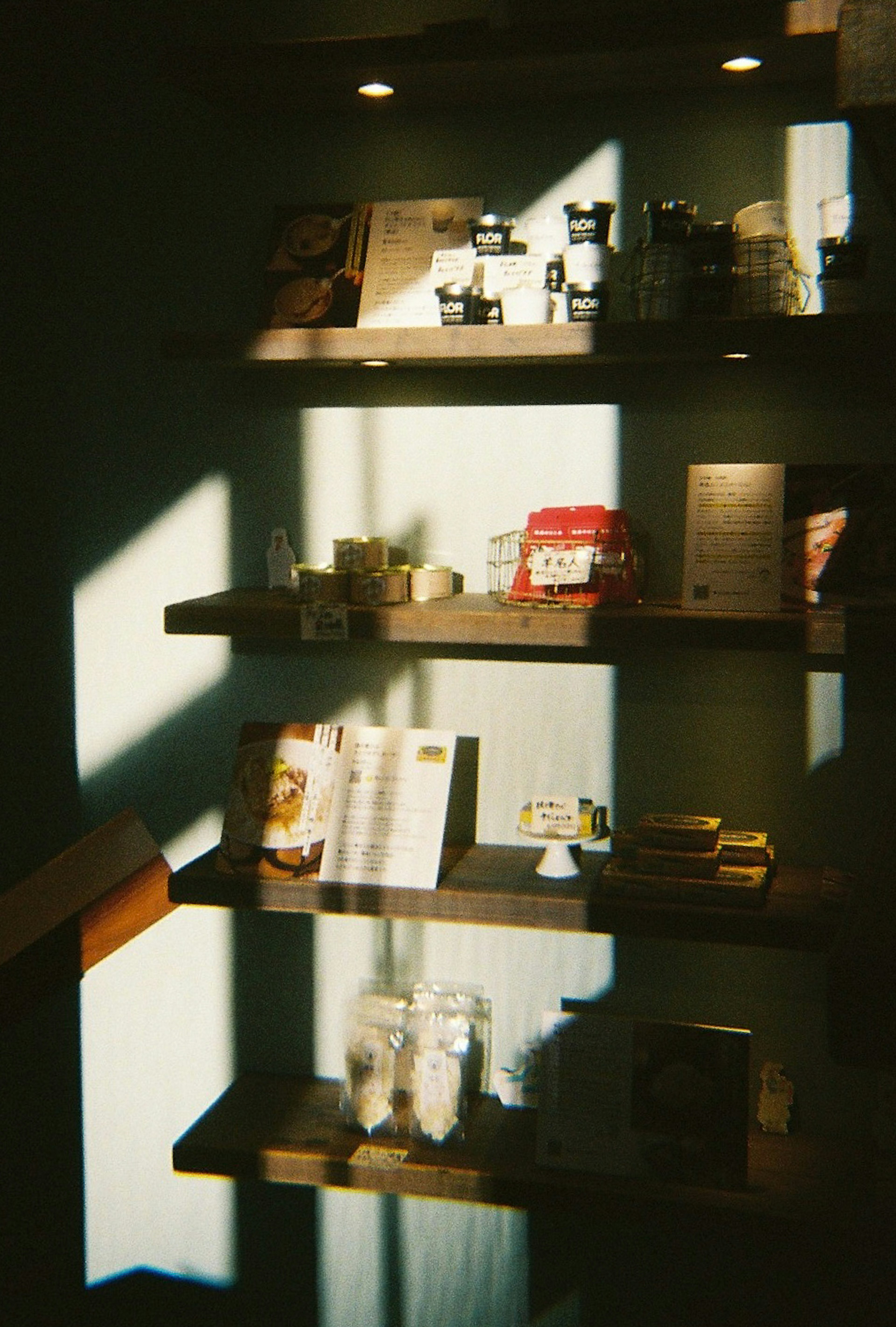 A wall shelf displaying jars and books with beautiful light and shadow play