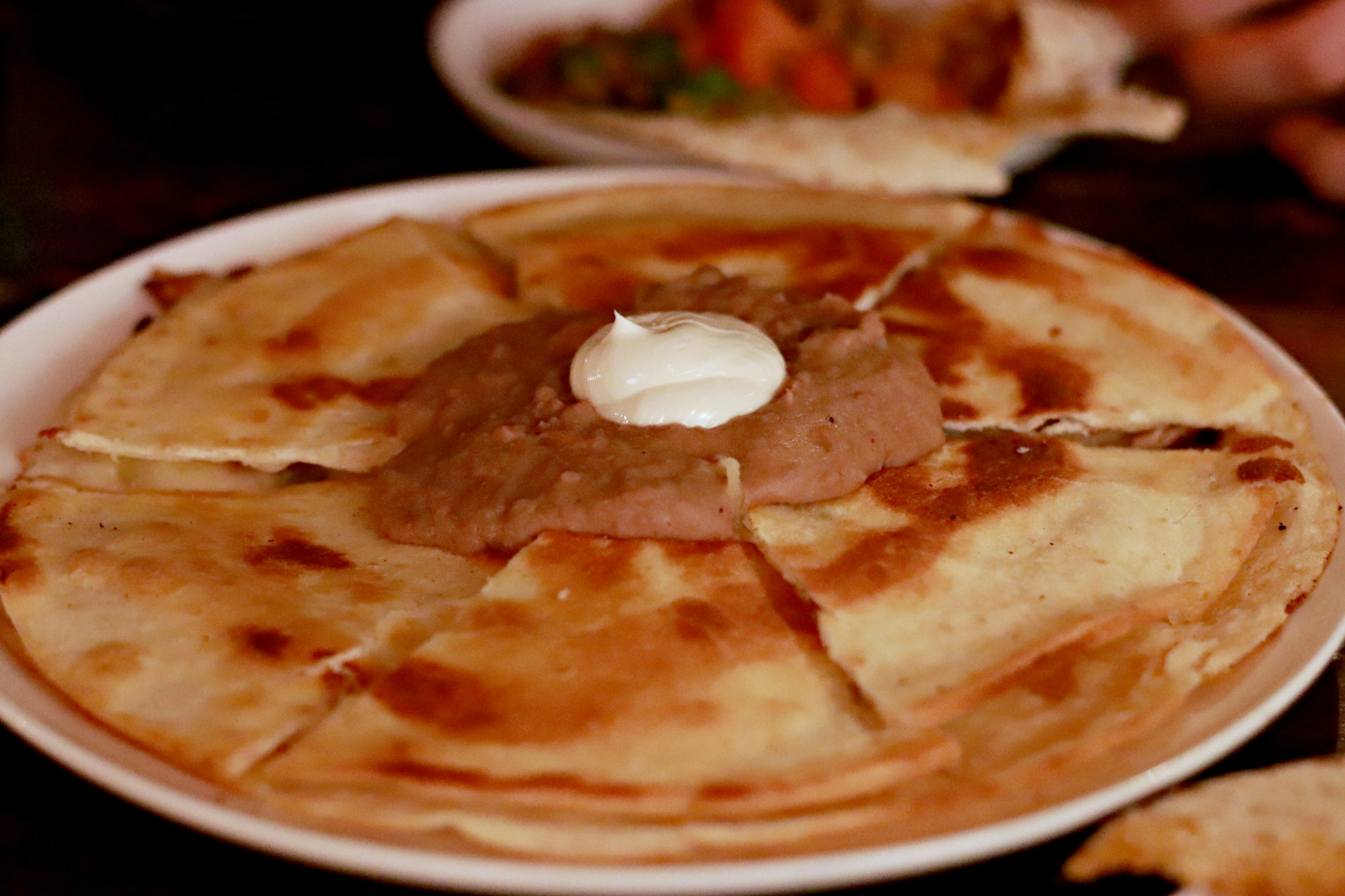 Quesadilla mexicana crujiente servida en un plato con crema agria