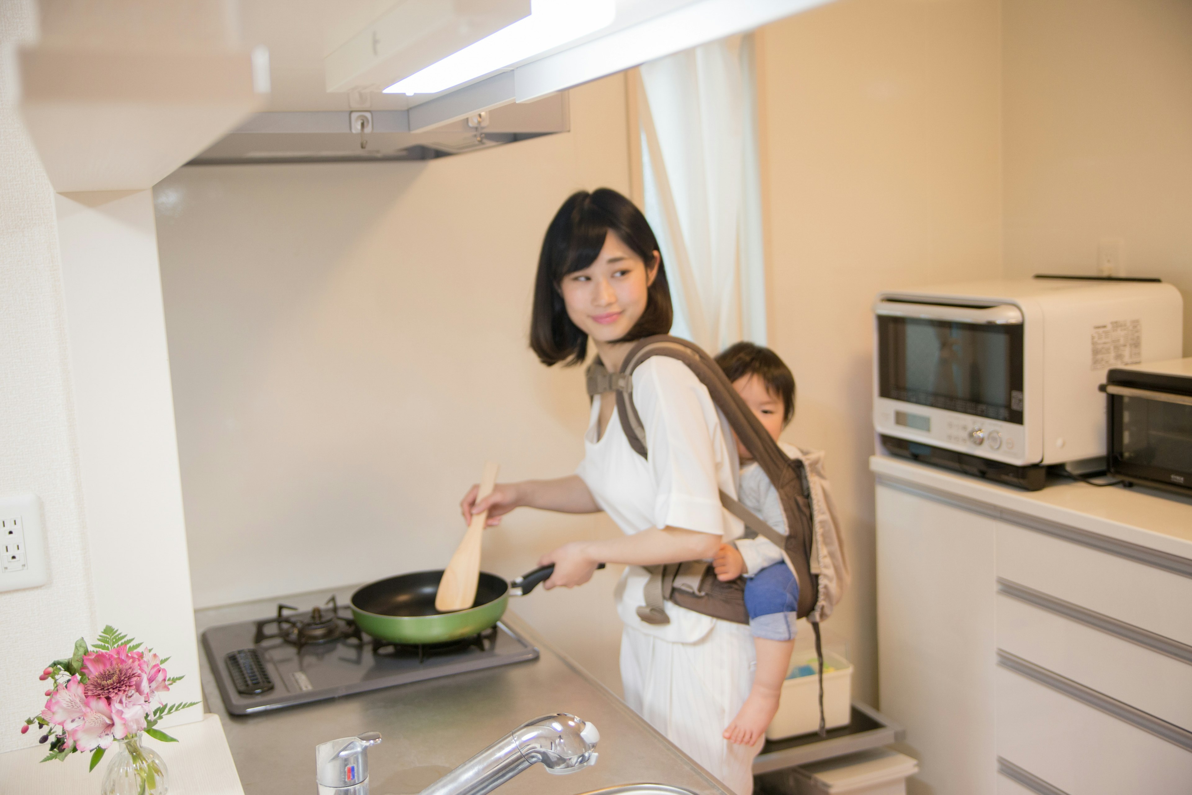 Donna che cucina in una cucina con un bambino sulla schiena