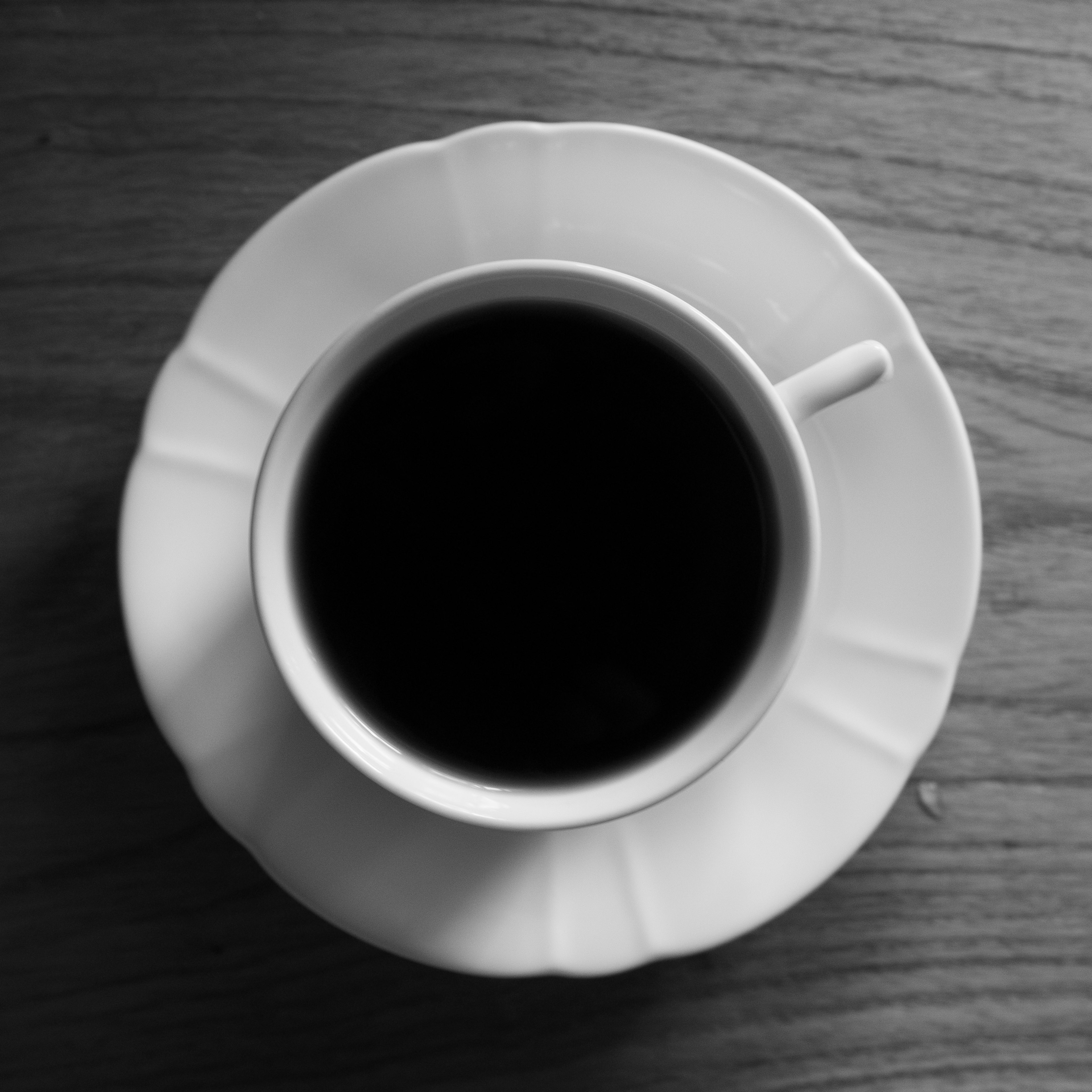 Vista superior de un café negro en una taza y platillo blancos