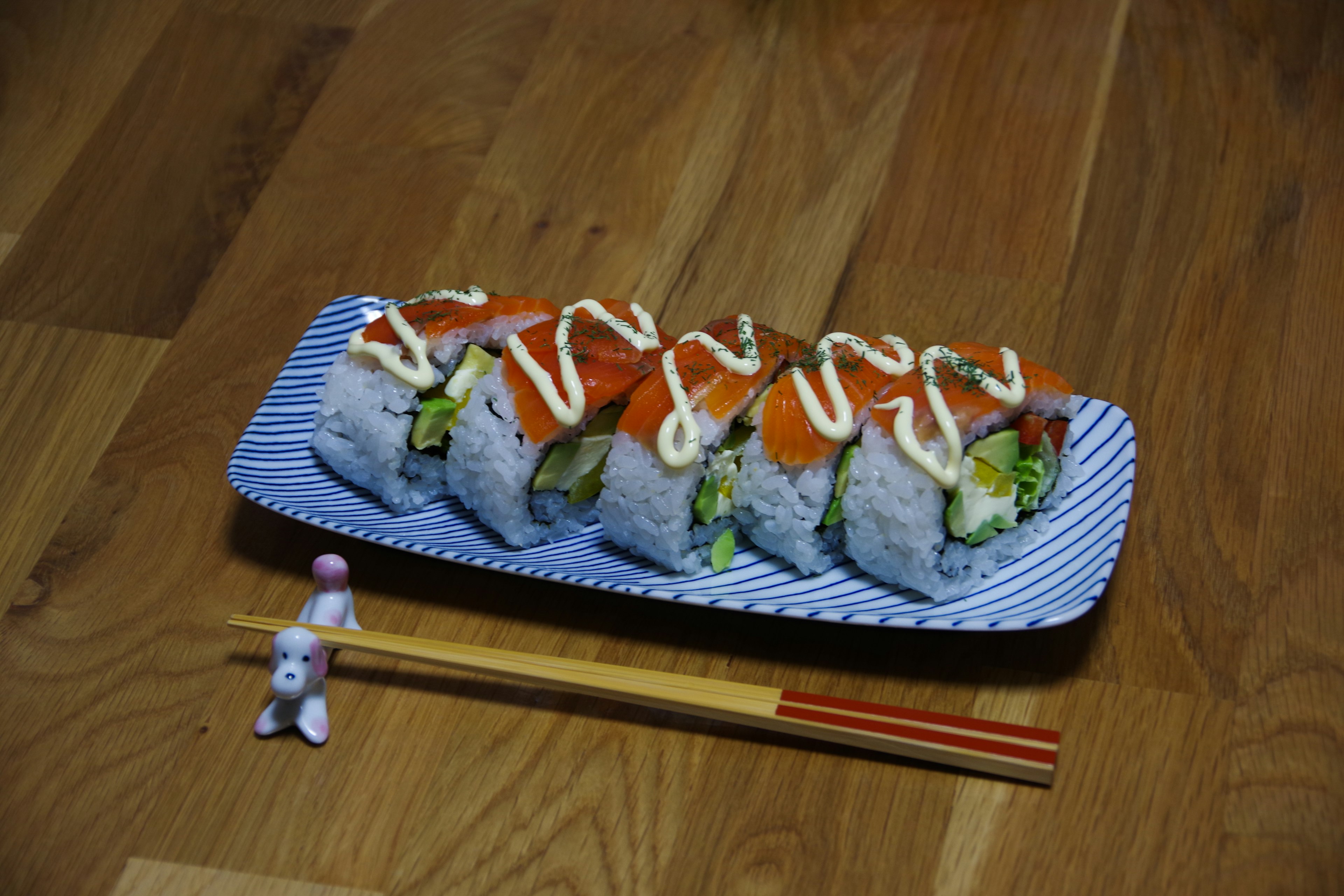 Sushi-Rollen auf einem blauen Teller mit Essstäbchen