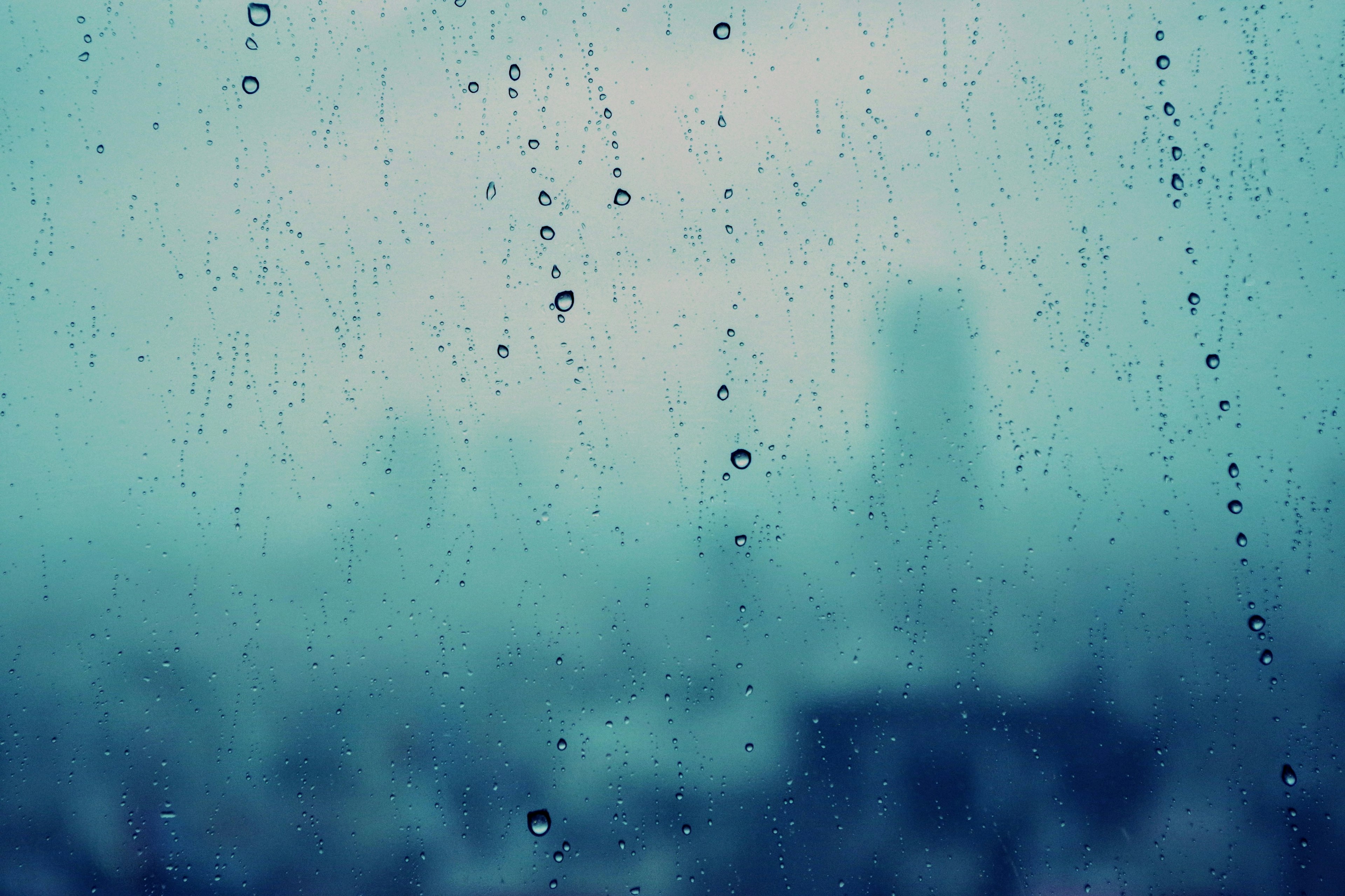 Paisaje urbano borroso visto a través de gotas de lluvia en una ventana