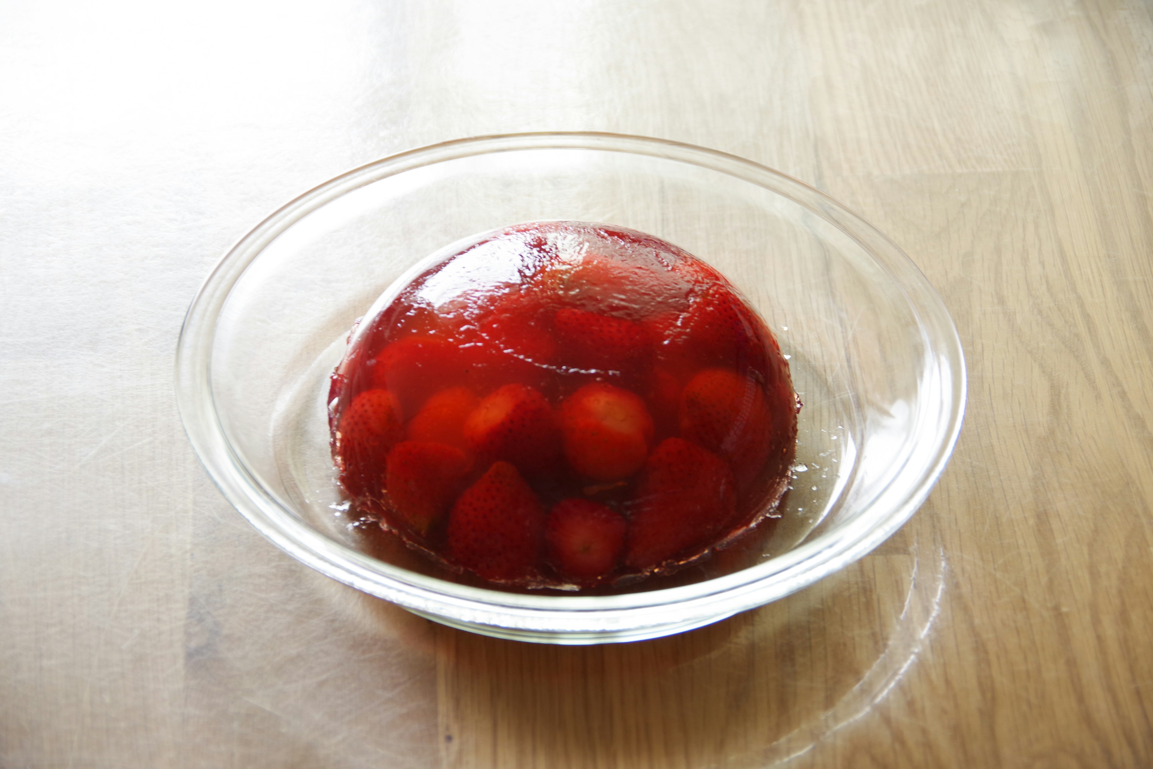 Postre de gelatina roja con frutas en un tazón transparente