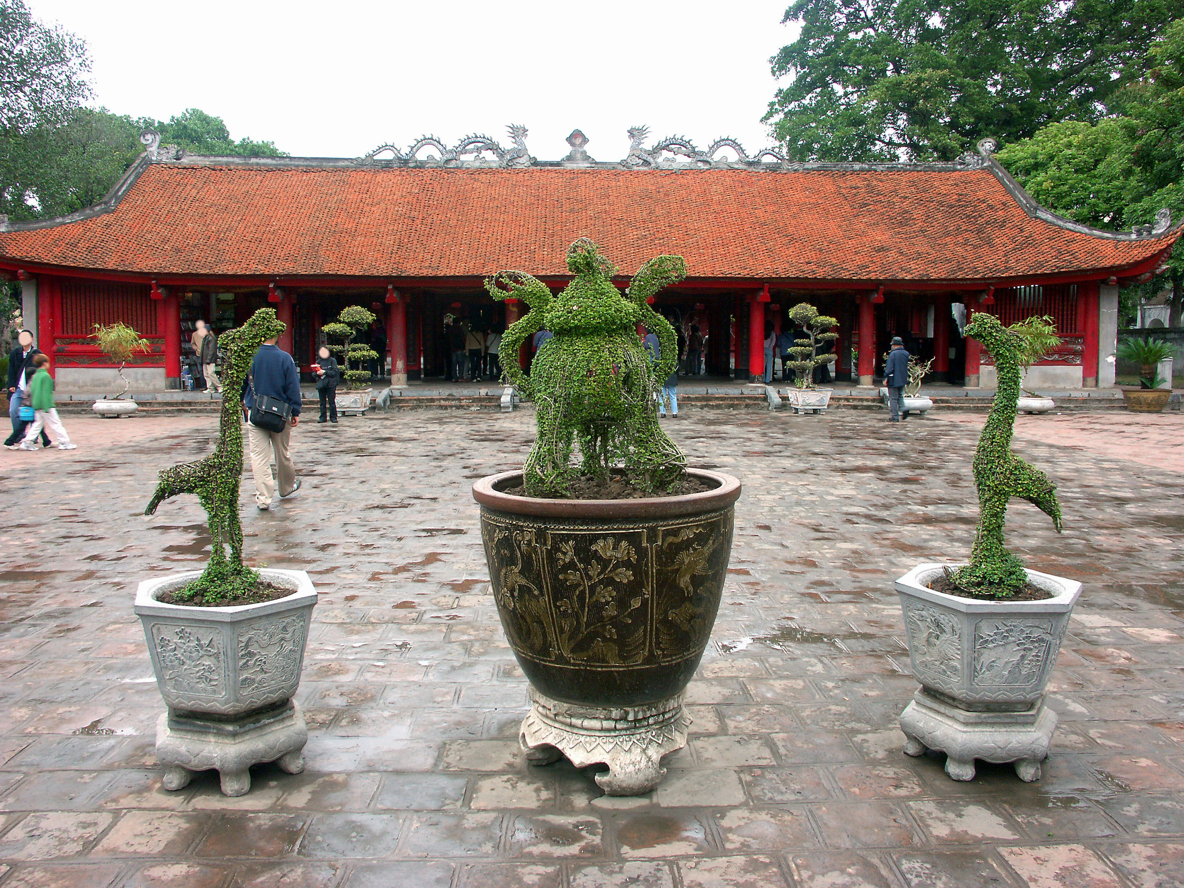 一个有红色屋顶建筑和绿色观赏植物的庭院