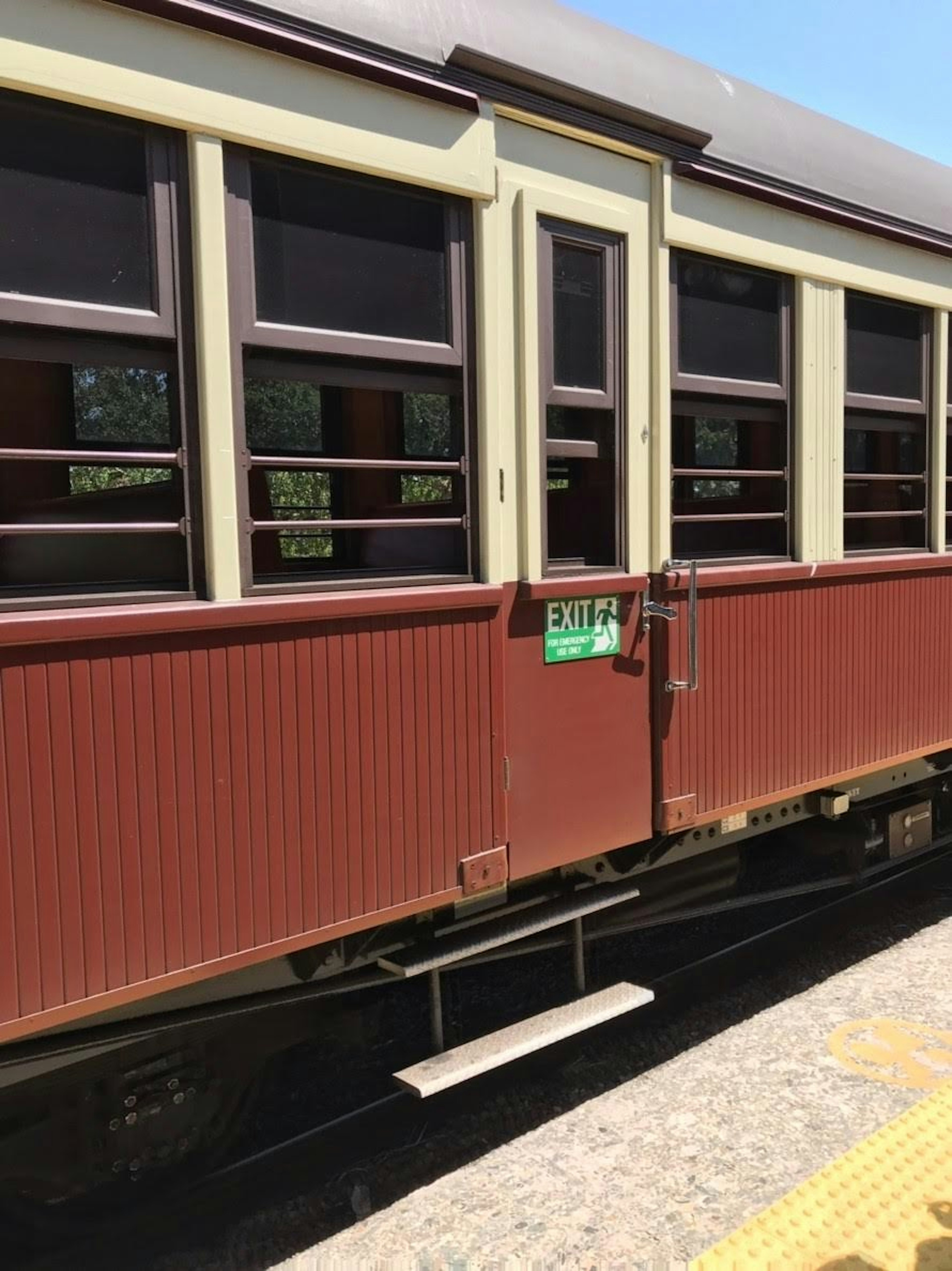 Tampilan samping kereta vintage berwarna coklat kemerahan dengan banyak jendela