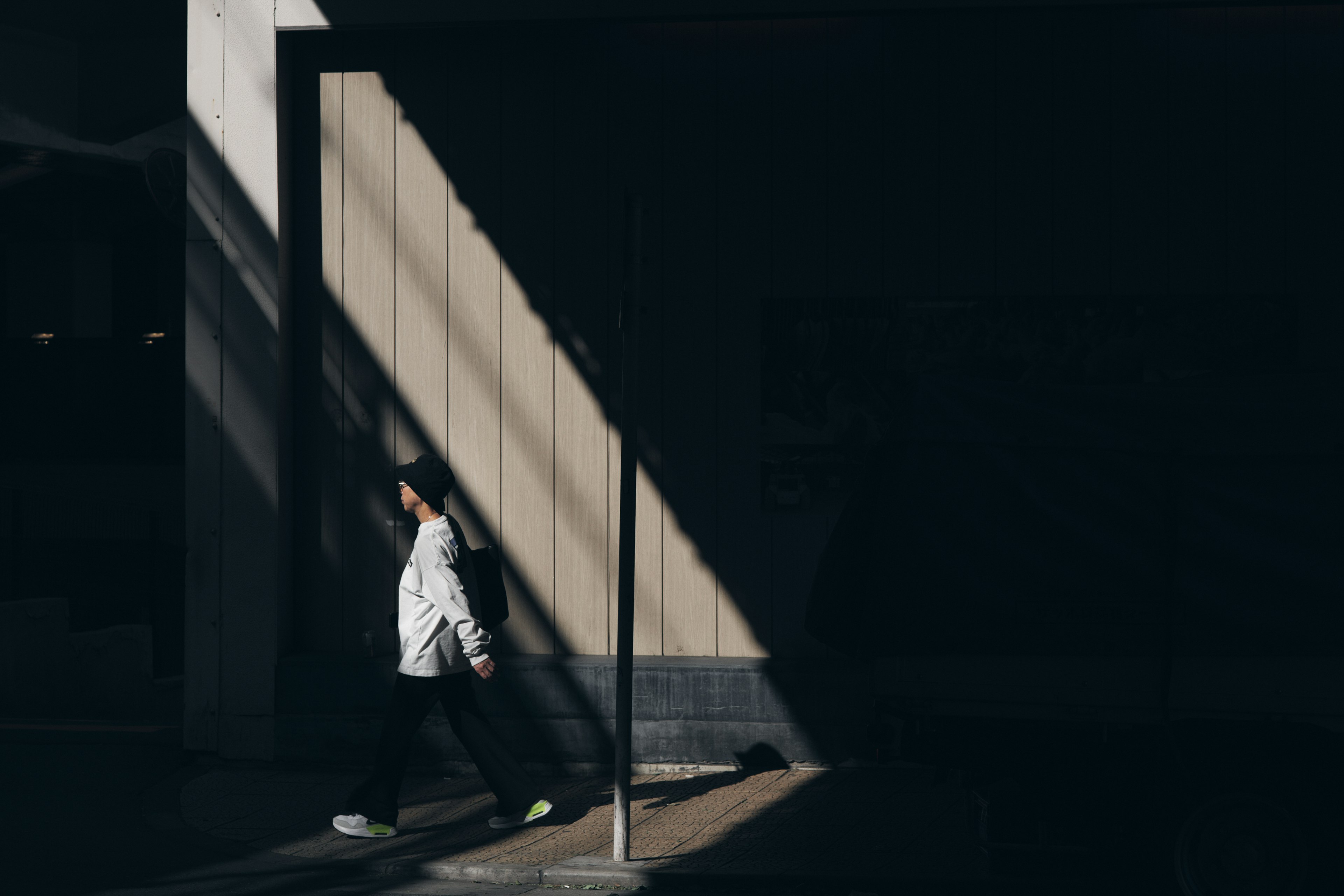 Eine Person, die gegen einen dunklen Hintergrund mit diagonalen Lichtschatten geht