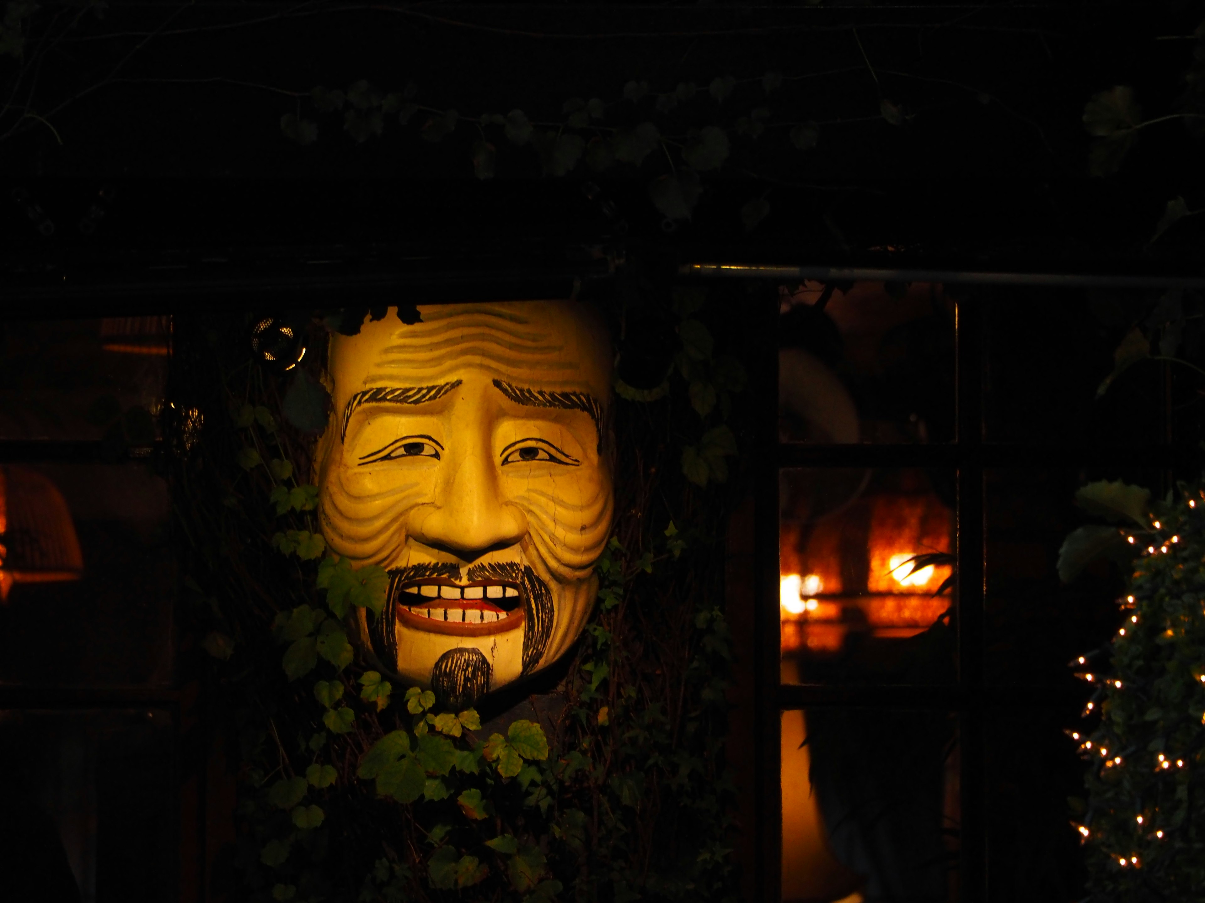 Un masque jaune illuminé la nuit entouré de feuilles vertes