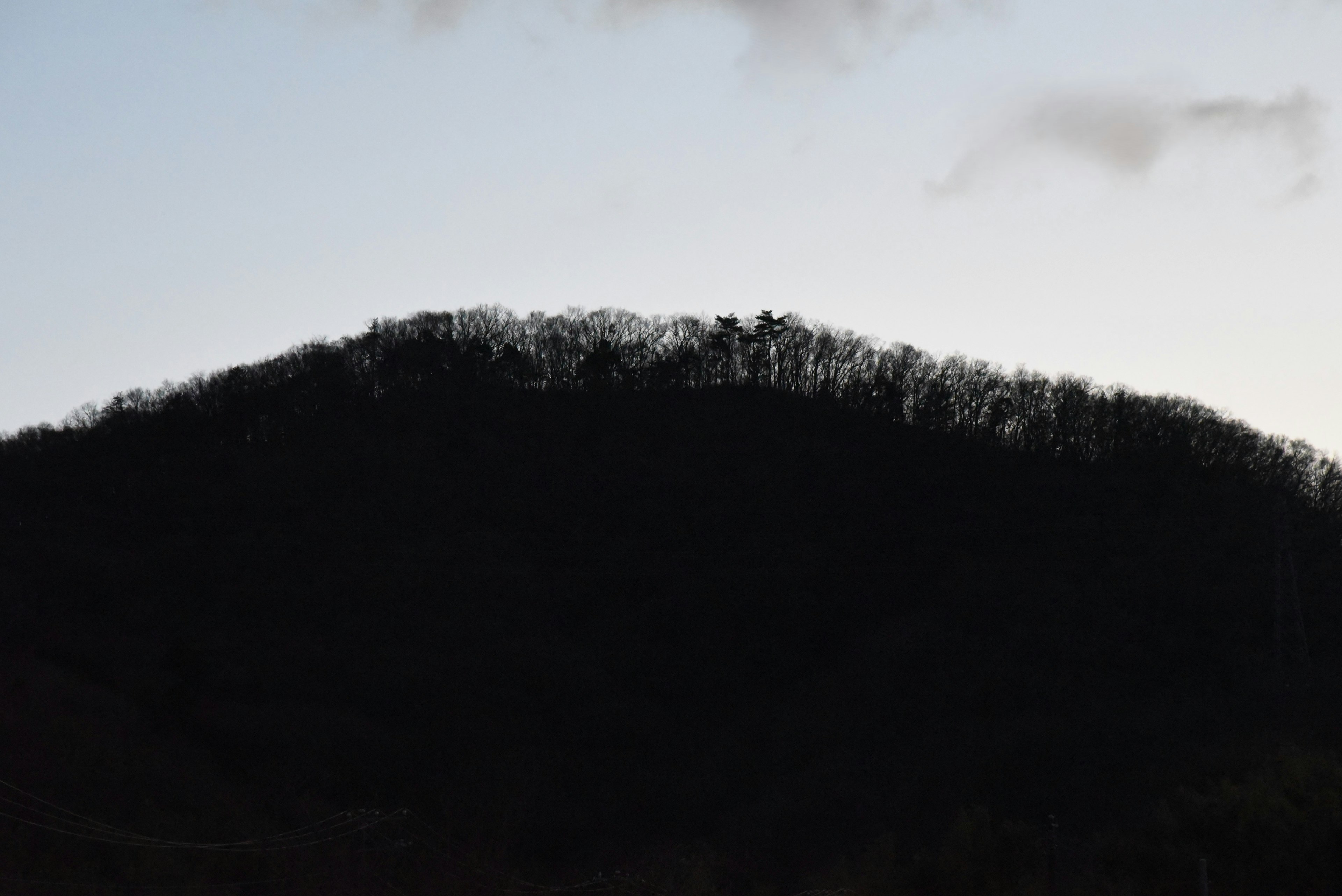 Silhouette di una collina al crepuscolo con un cielo debolmente illuminato