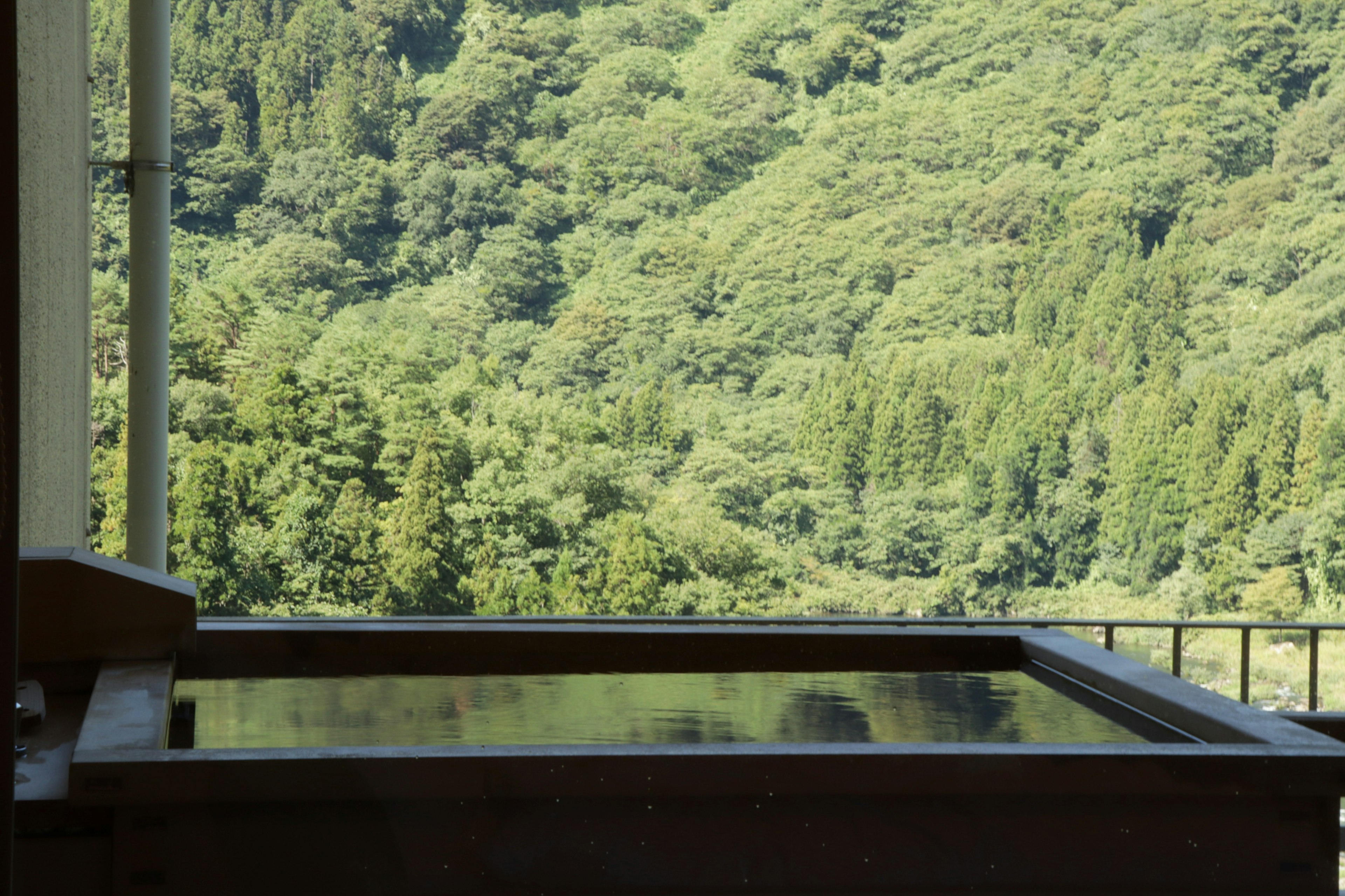 View of an outdoor hot spring overlooking lush green mountains