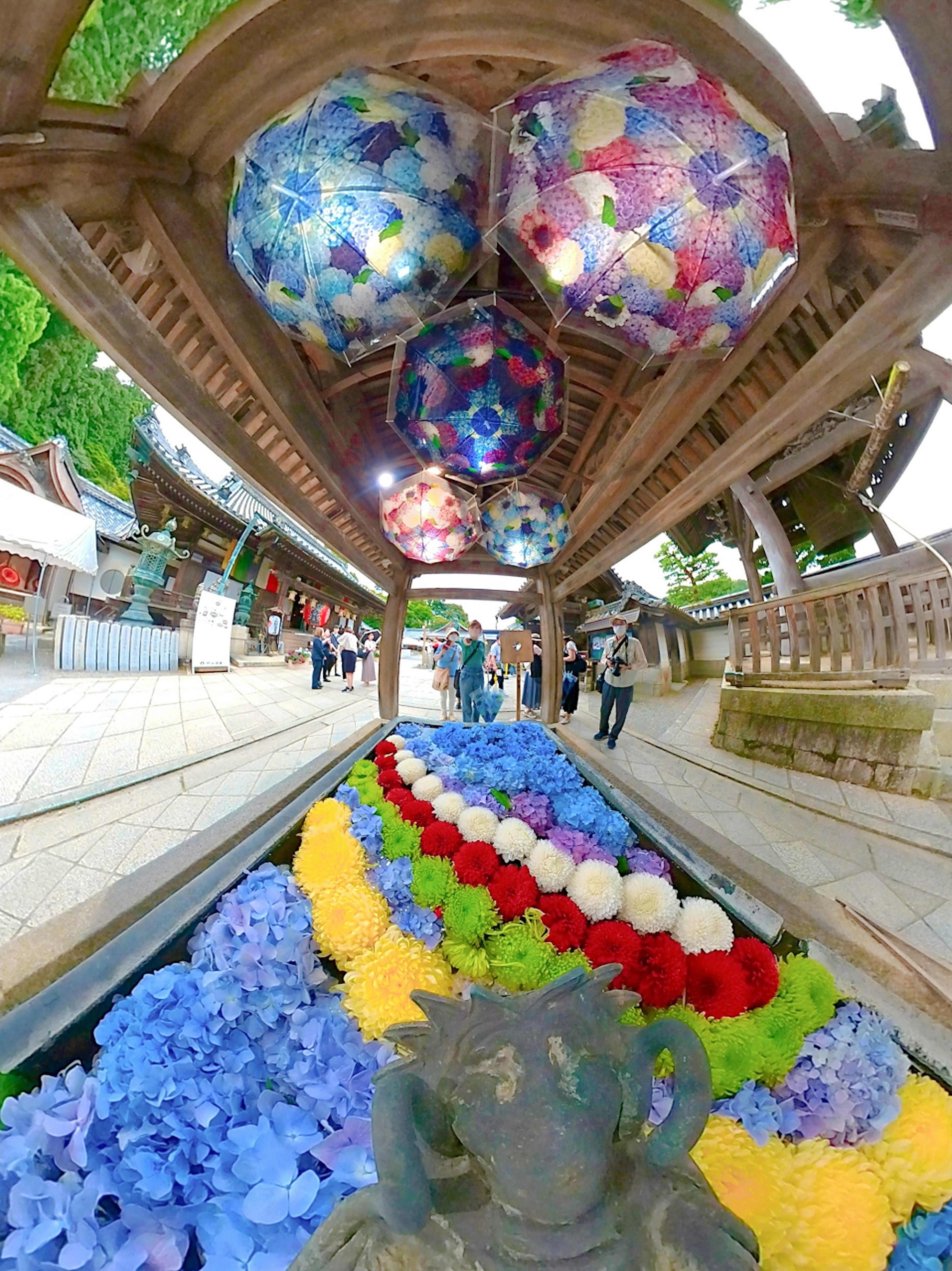 色とりどりの花が並ぶ神社の参道と装飾された傘