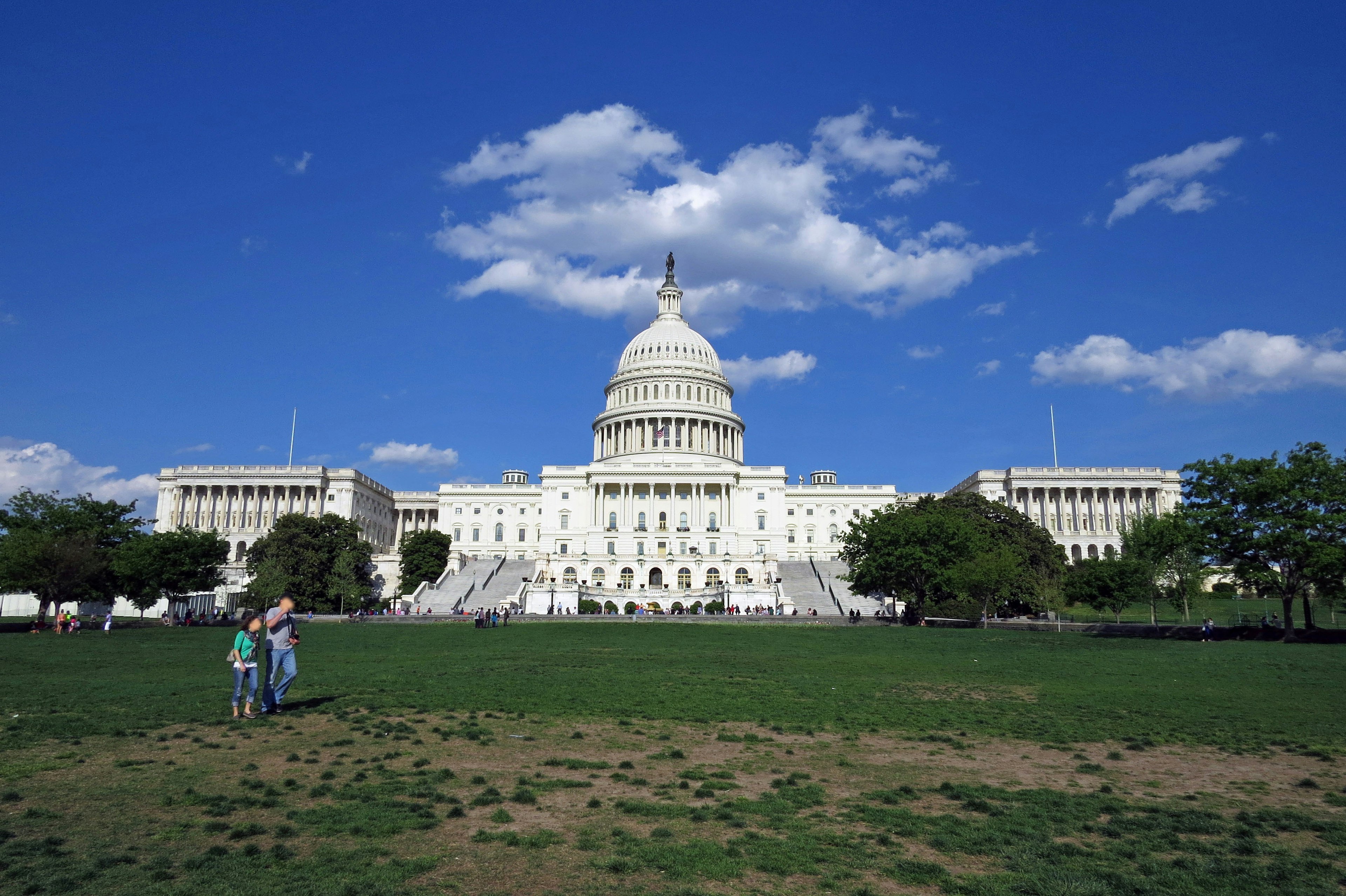 United States Capitol building with a clear blue sky and green lawn