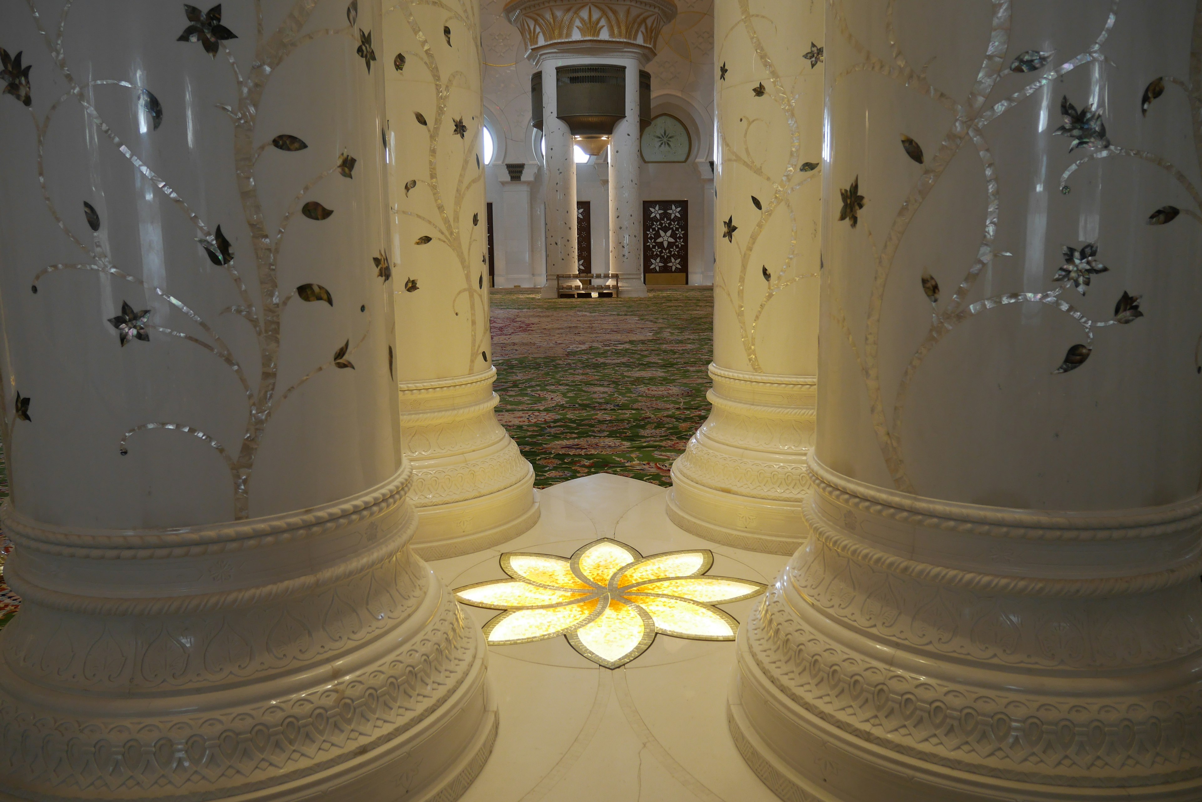 Illuminated flower design on the floor between ornate white pillars