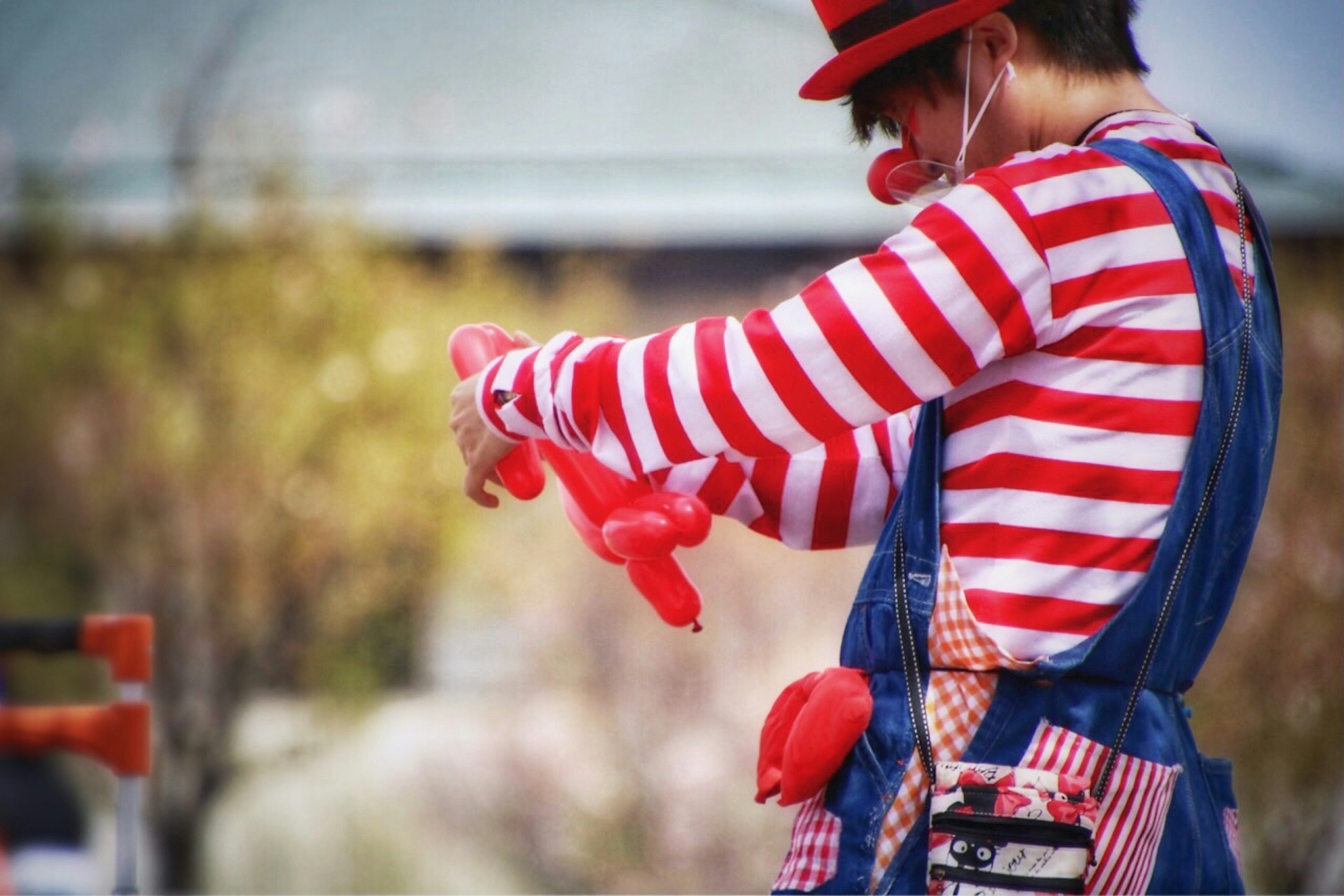 Un artista in camicia a righe rosse che crea animali di palloncino