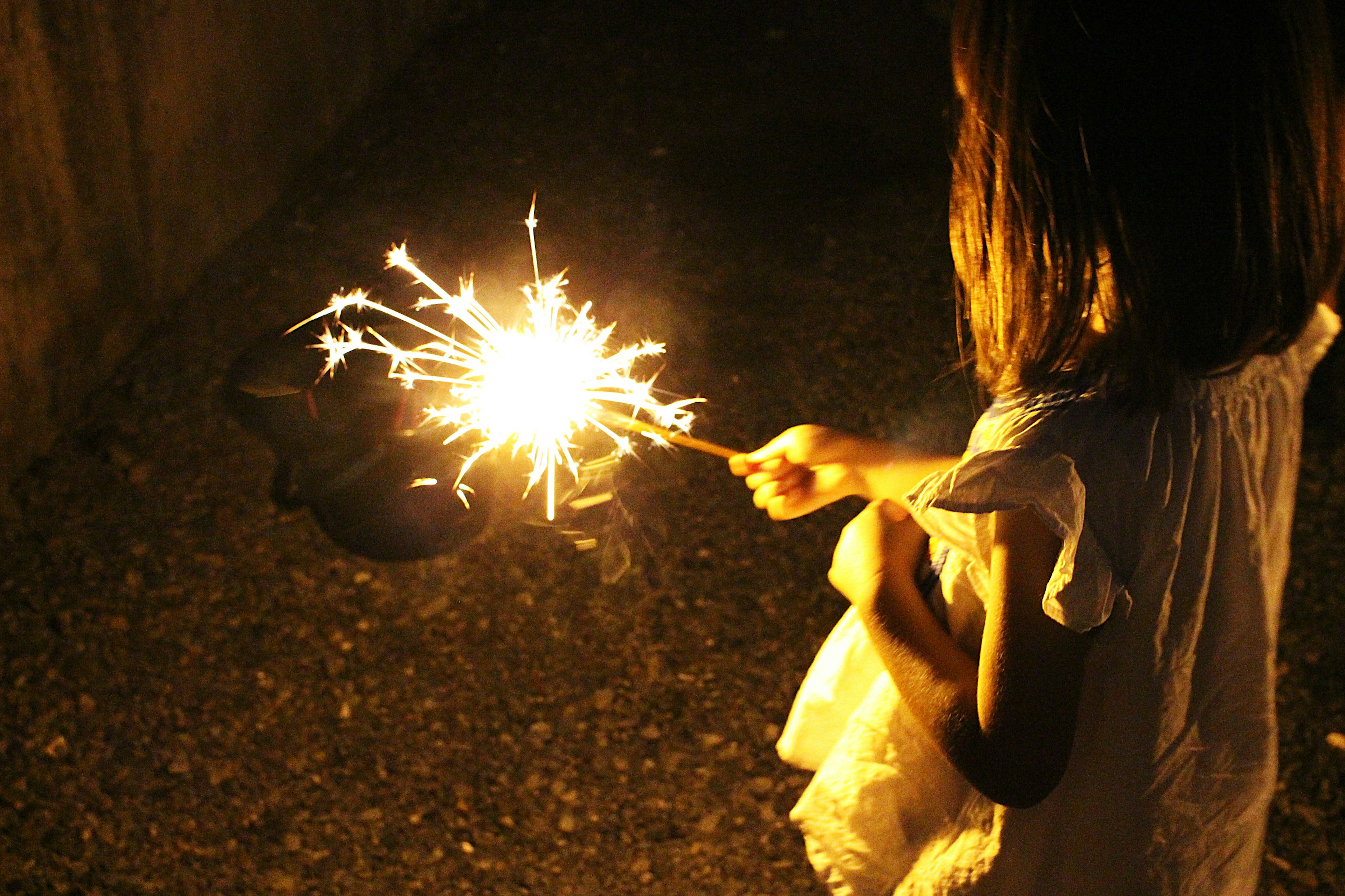 Niño sosteniendo un fuego artificial en la oscuridad