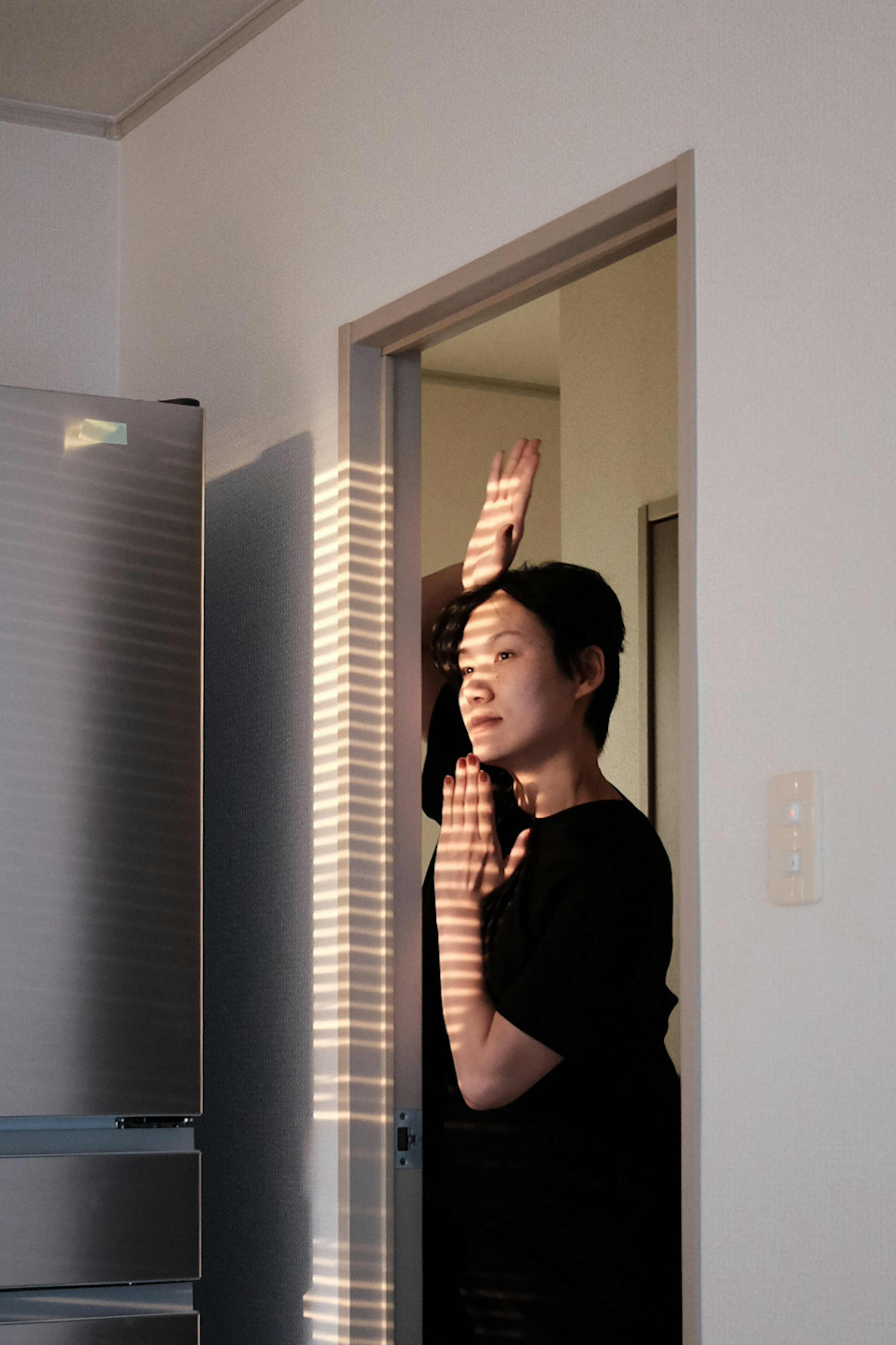 Mujer posando cerca de una puerta con la luz del sol creando sombras