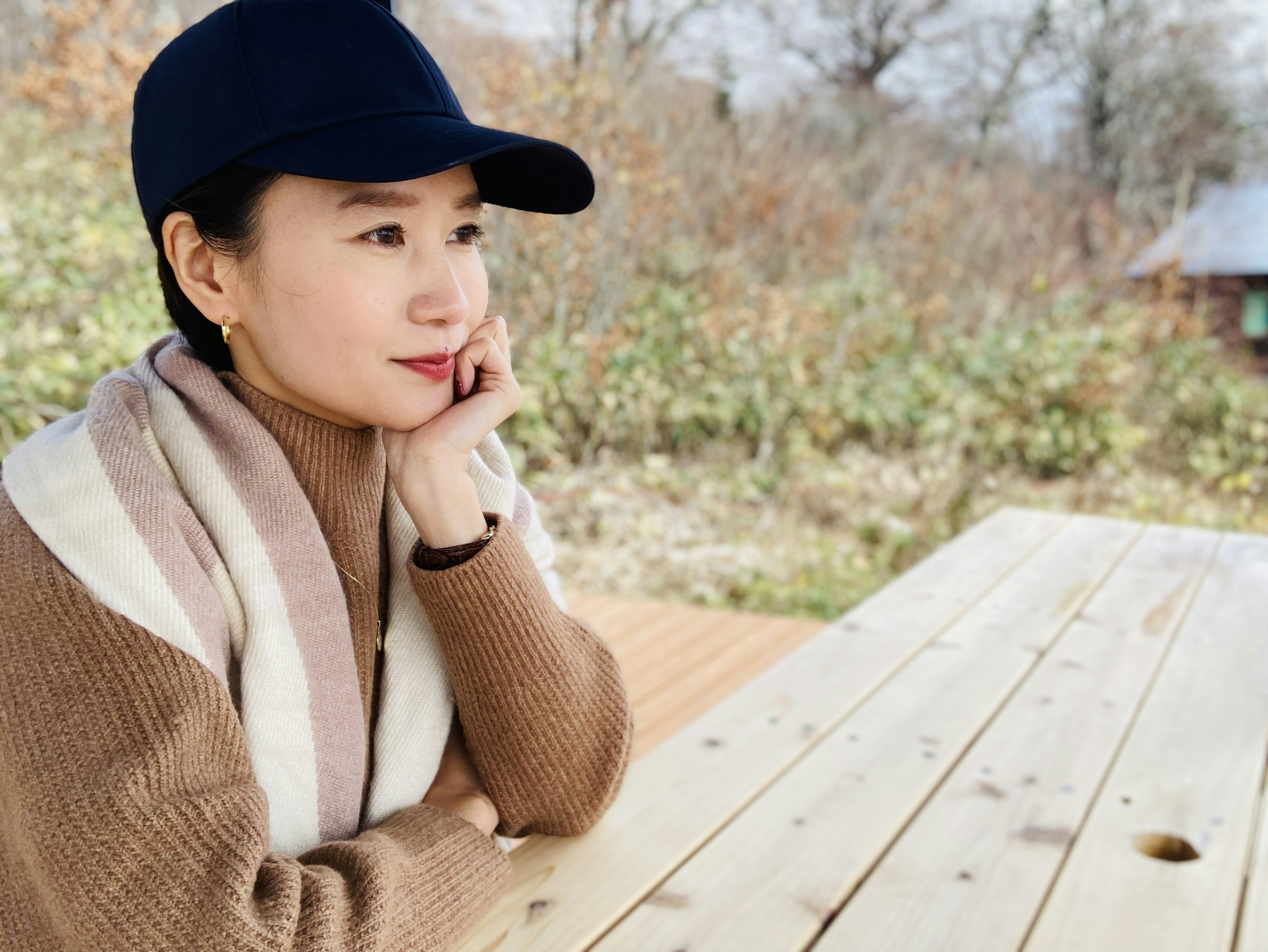 A woman sitting at a wooden table looking thoughtful