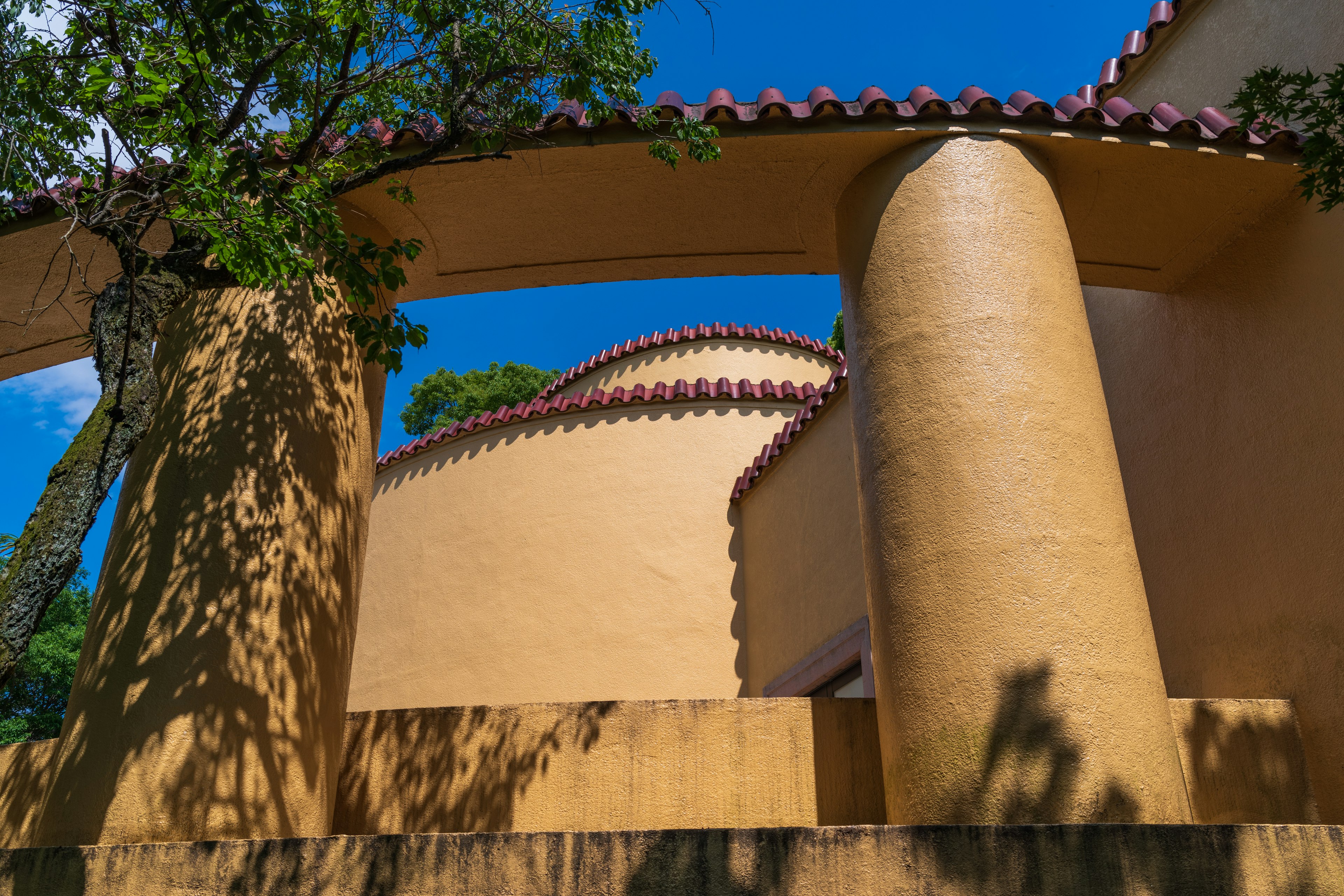 Estructura arquitectónica única con colores cálidos y sombras bajo un cielo azul