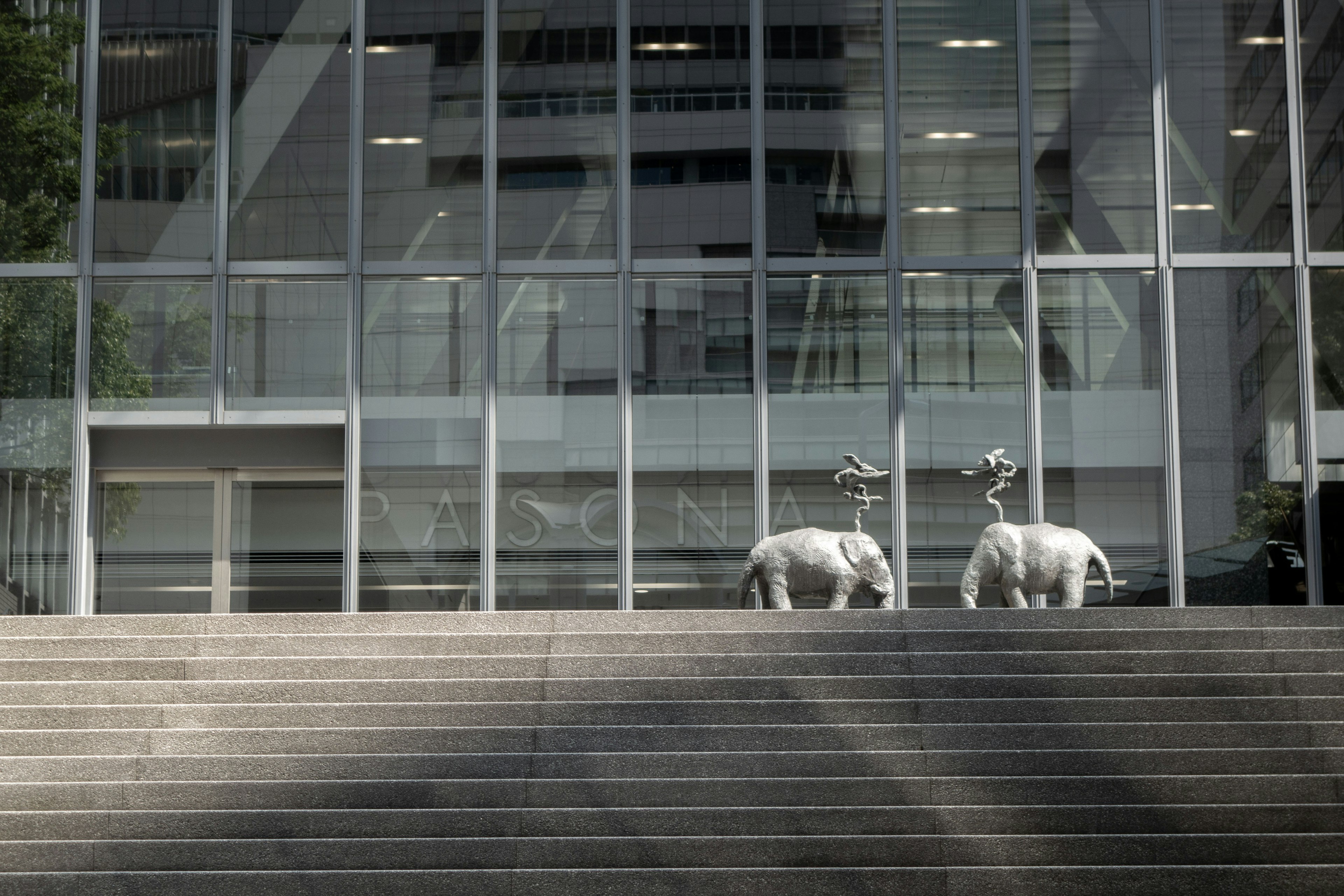 Deux sculptures de moutons blancs devant un bâtiment moderne