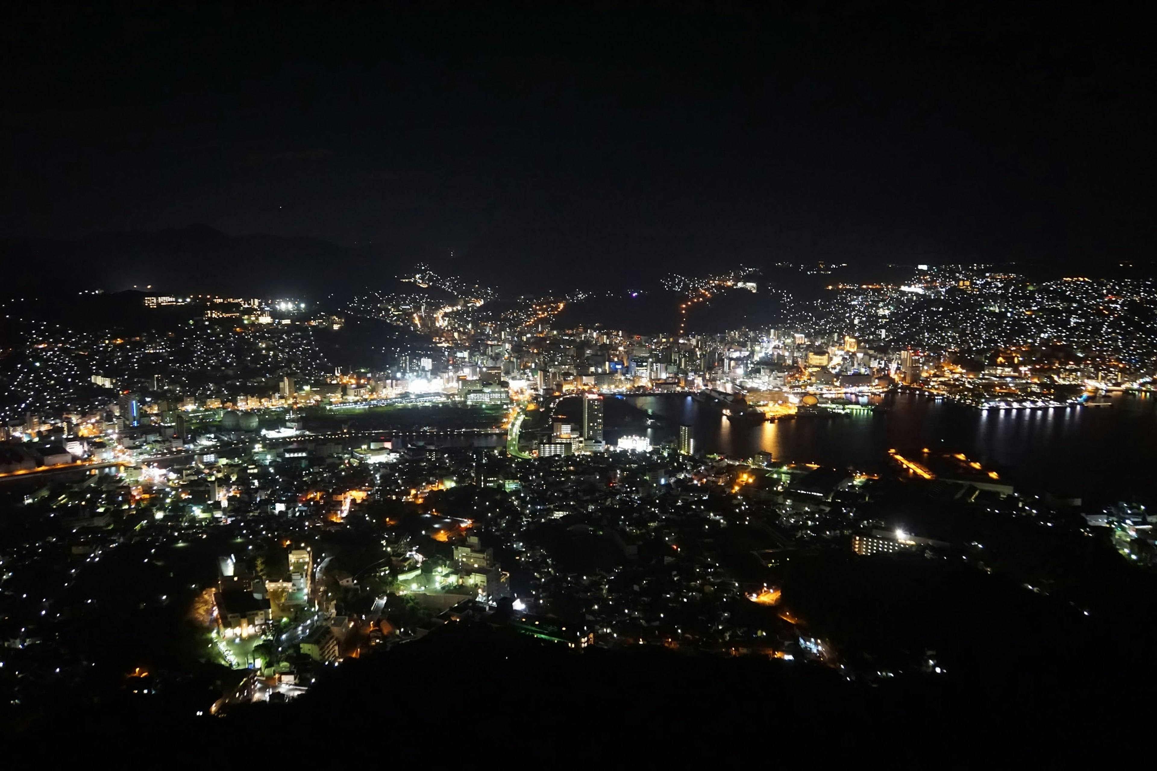 Paisaje urbano nocturno con luces brillantes iluminando la costa