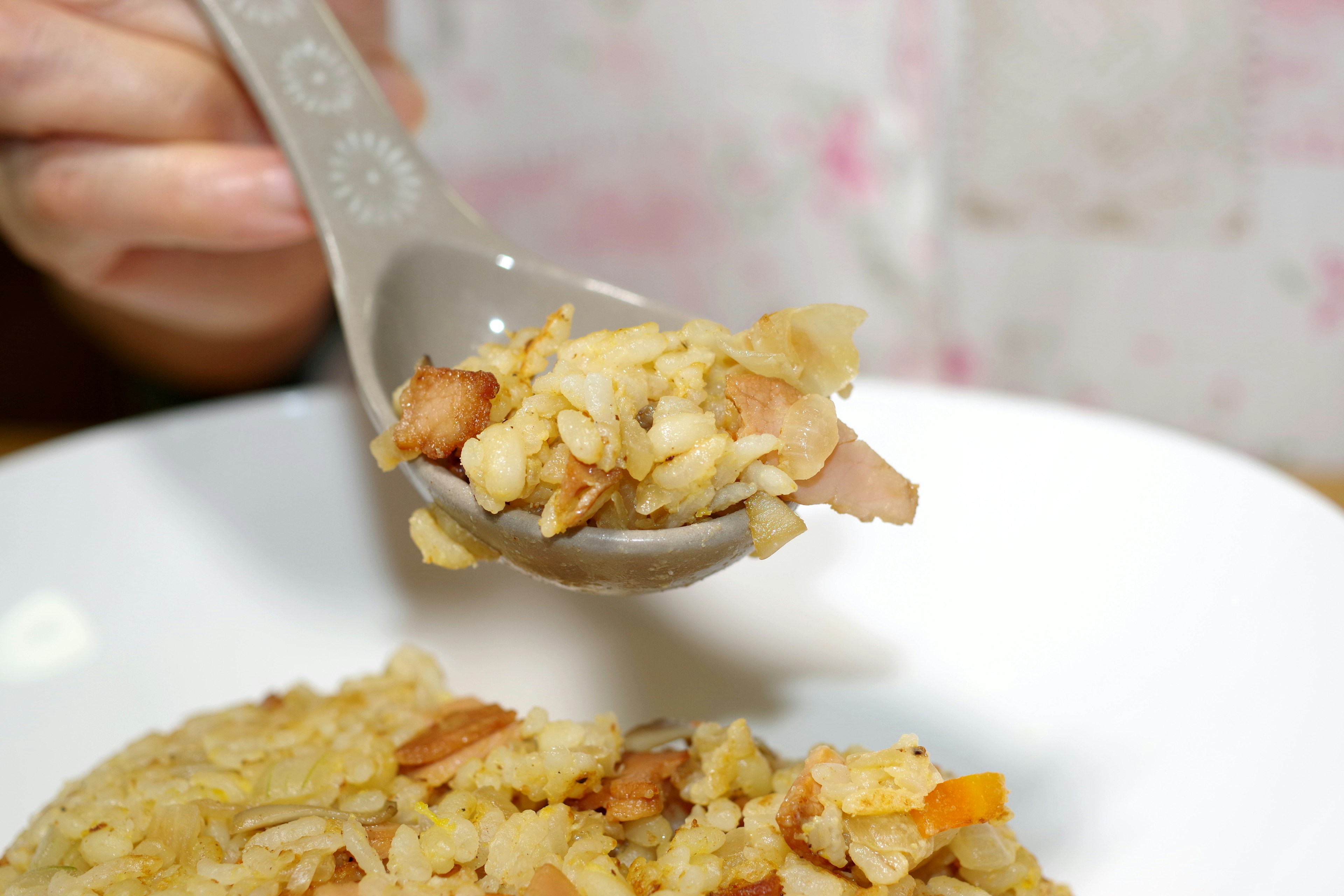 Close-up of a spoonful of rice and ingredients held in a hand