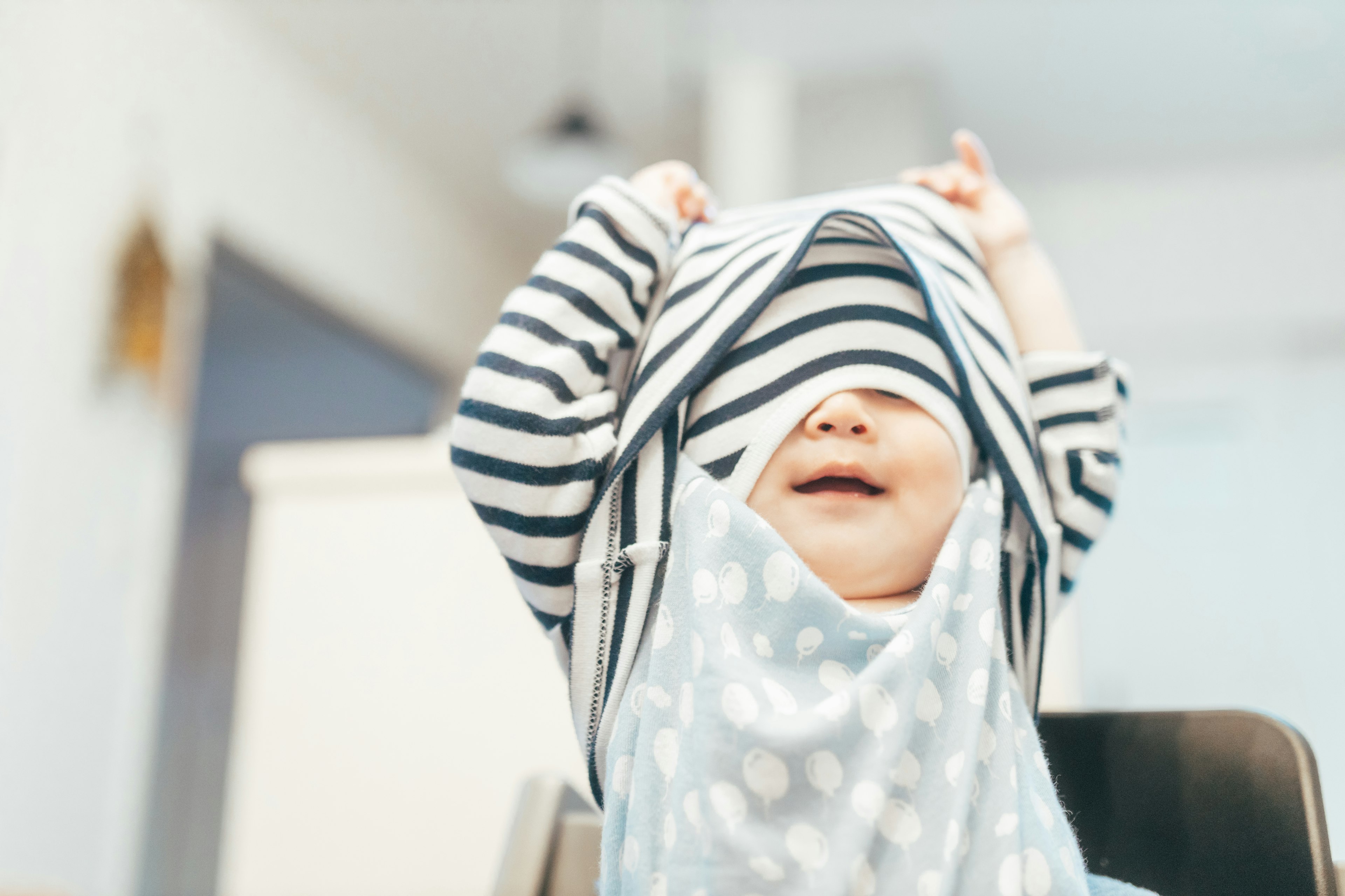 Bébé jouant avec un chapeau rayé et souriant