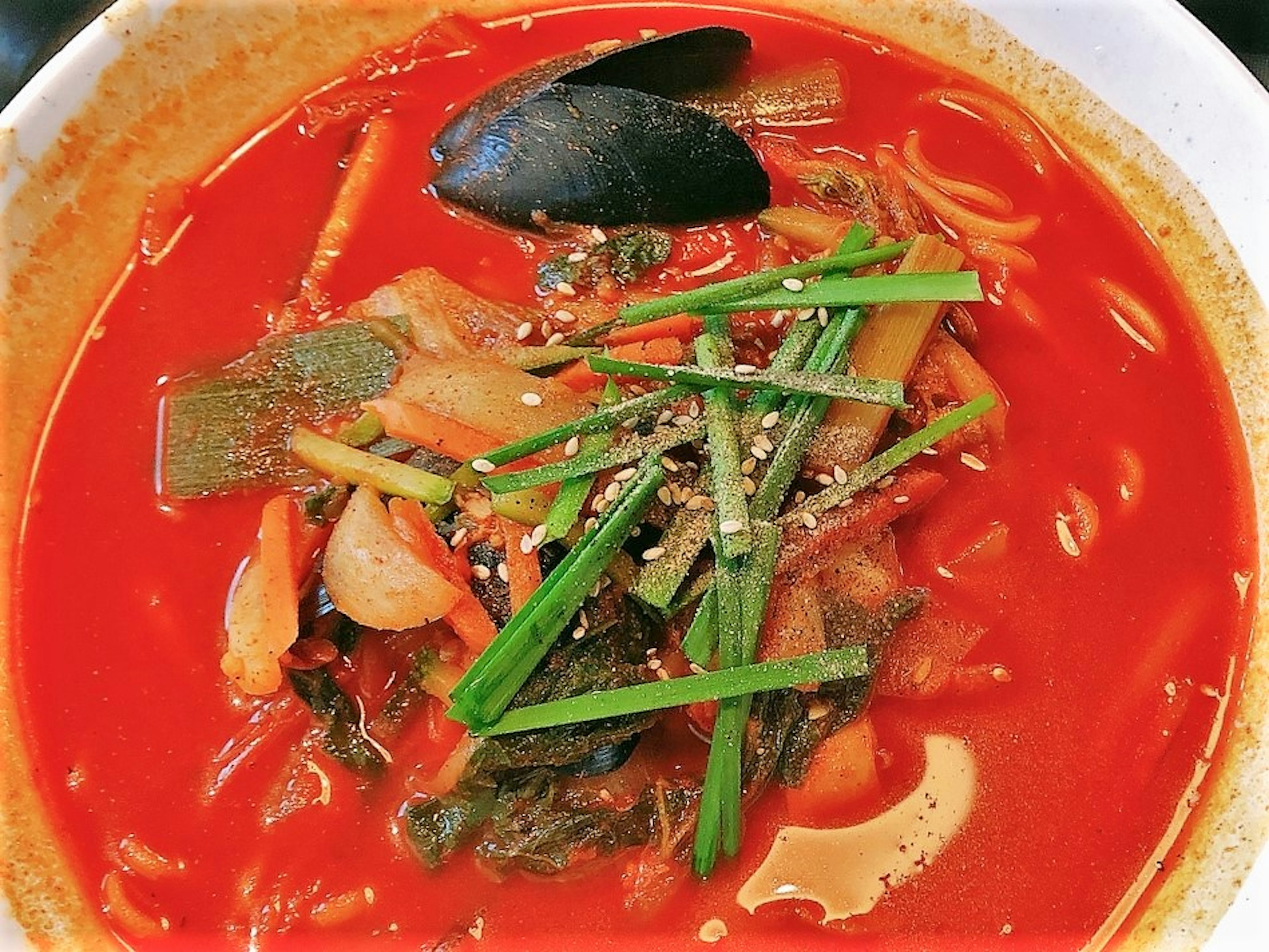 Una sopa roja vibrante llena de verduras y mariscos