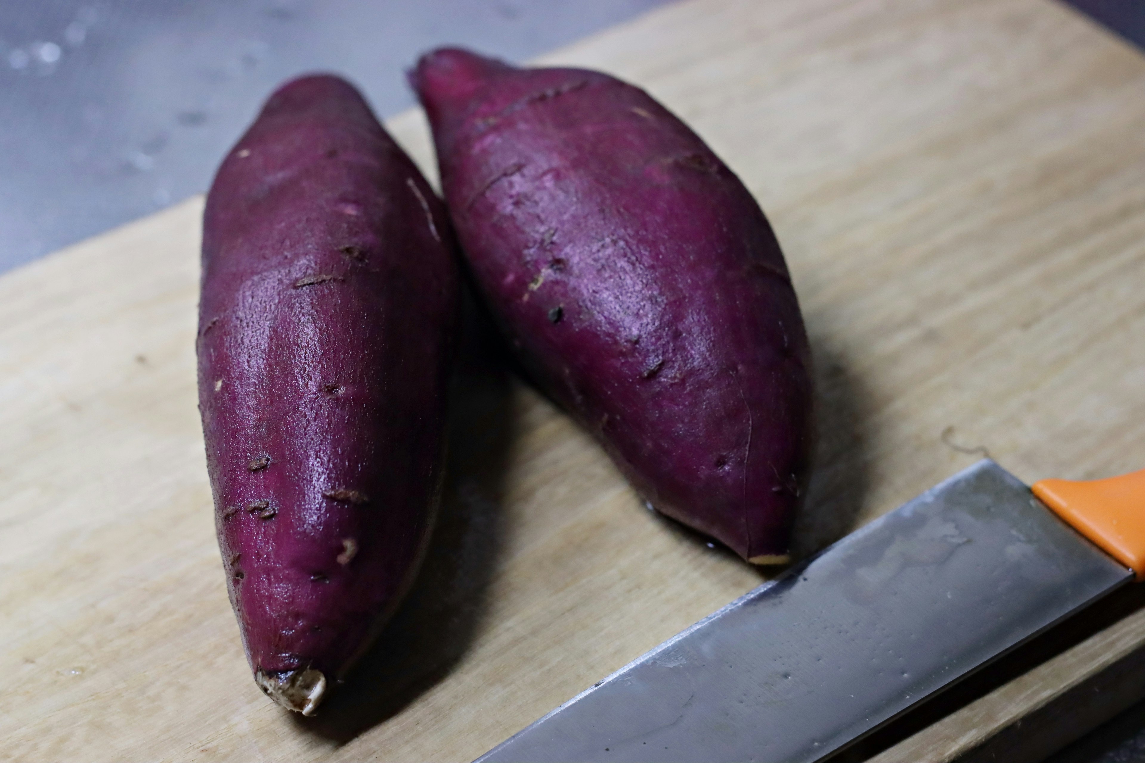 Deux patates douces violettes sur une planche à découper en bois