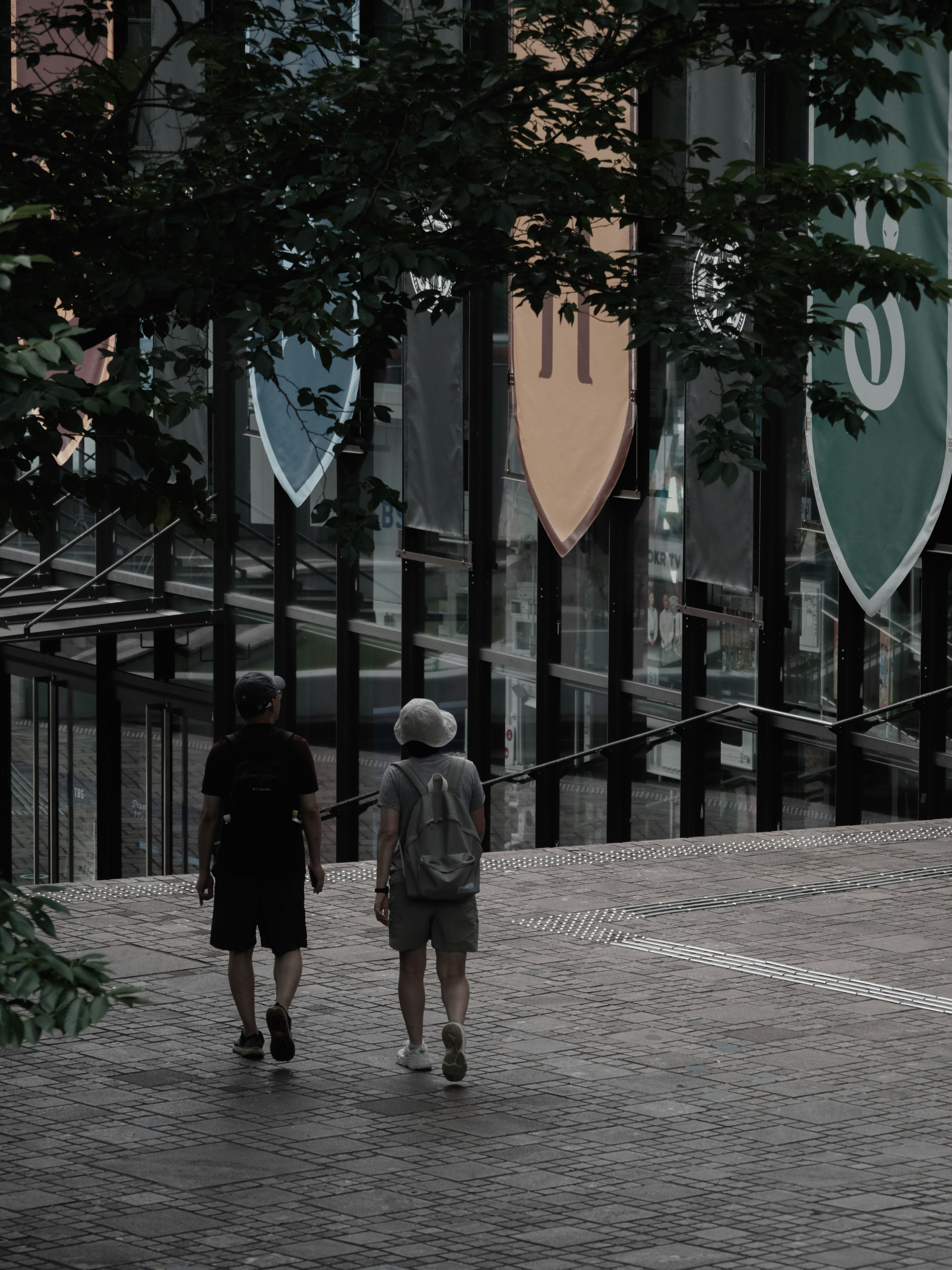 Two people walking away with colorful banners in the background