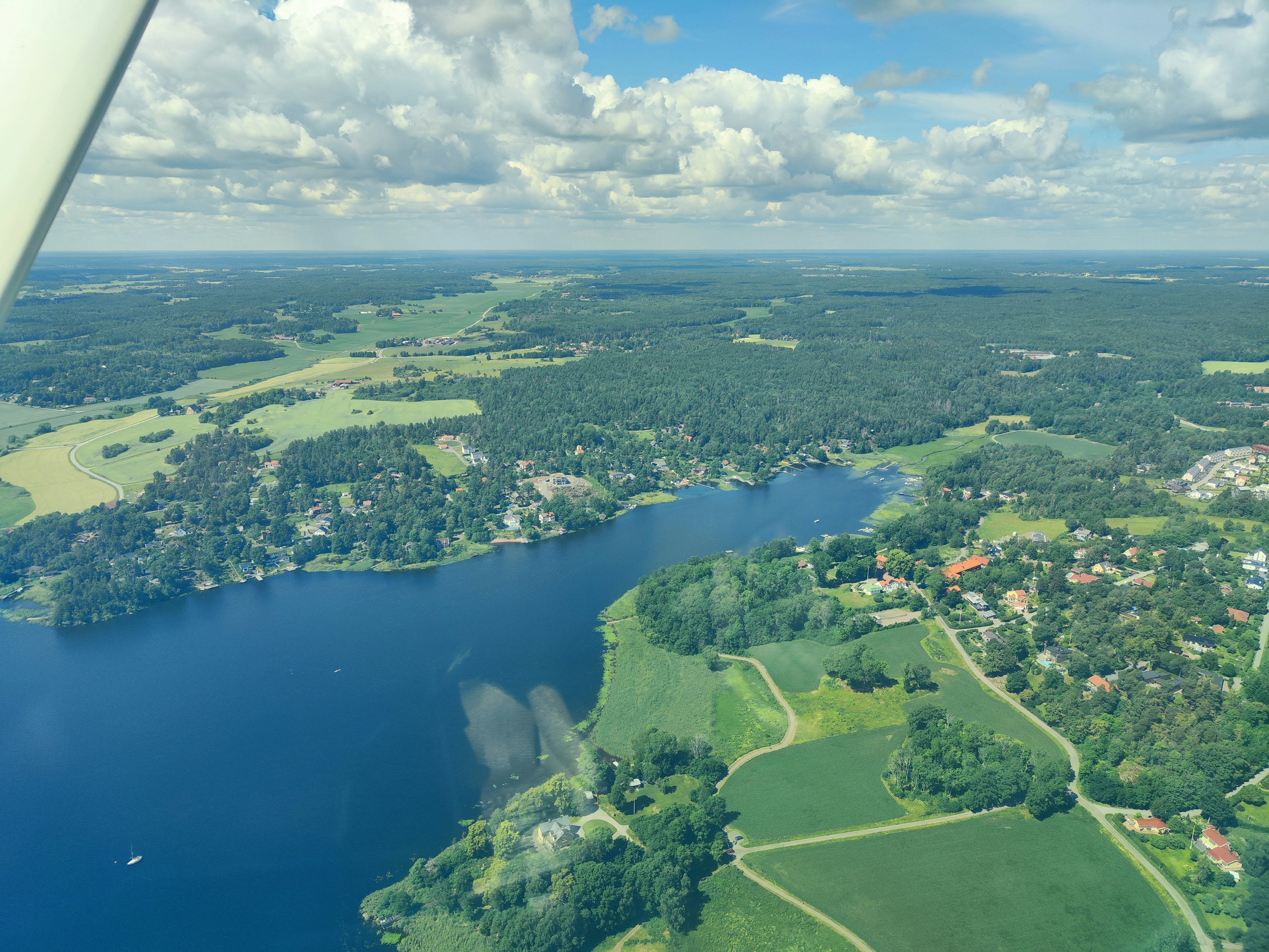 Vista aérea de un lago rodeado de vegetación exuberante y campos