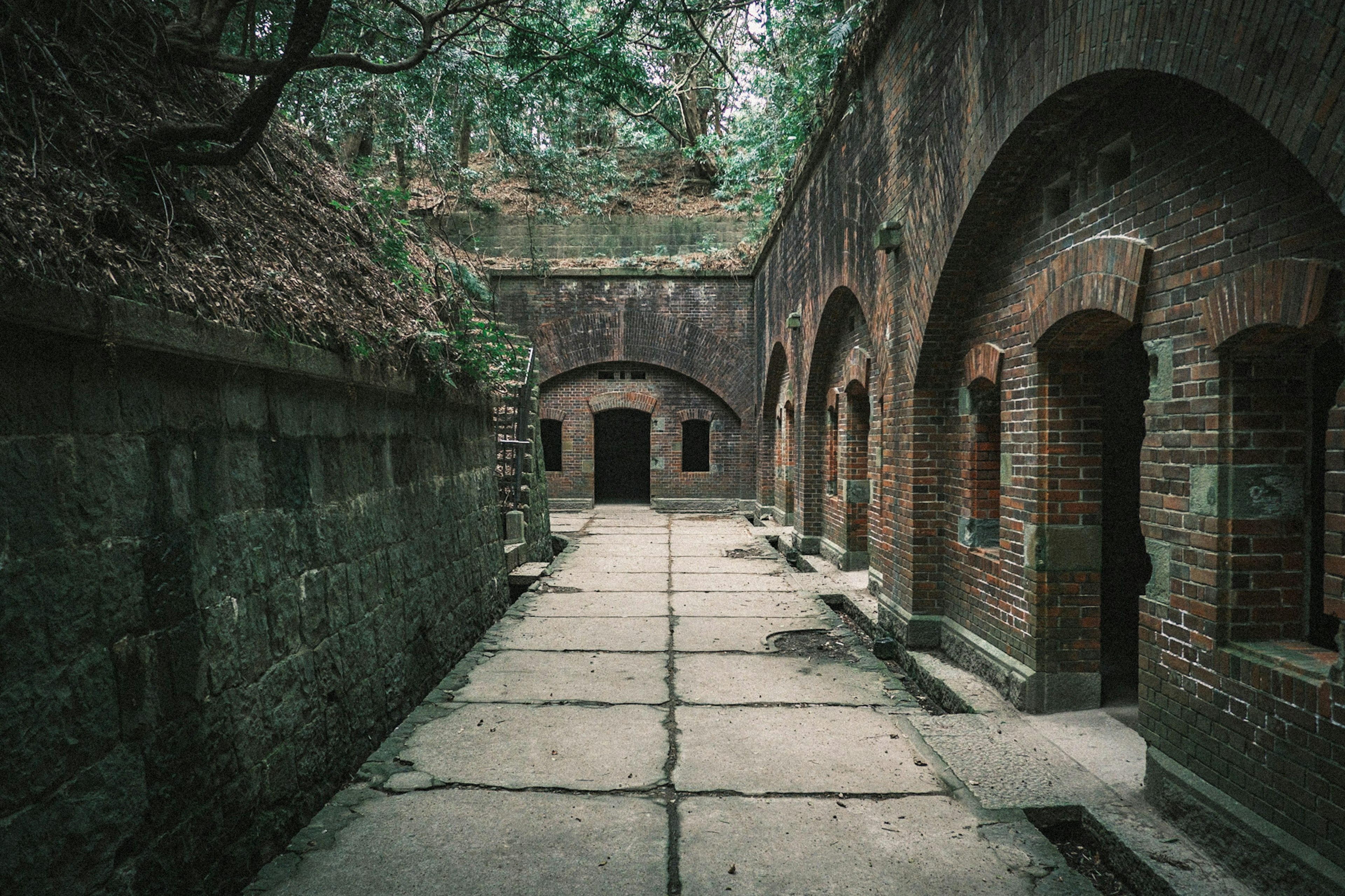 Historic brick buildings with arched pathways surrounded by greenery