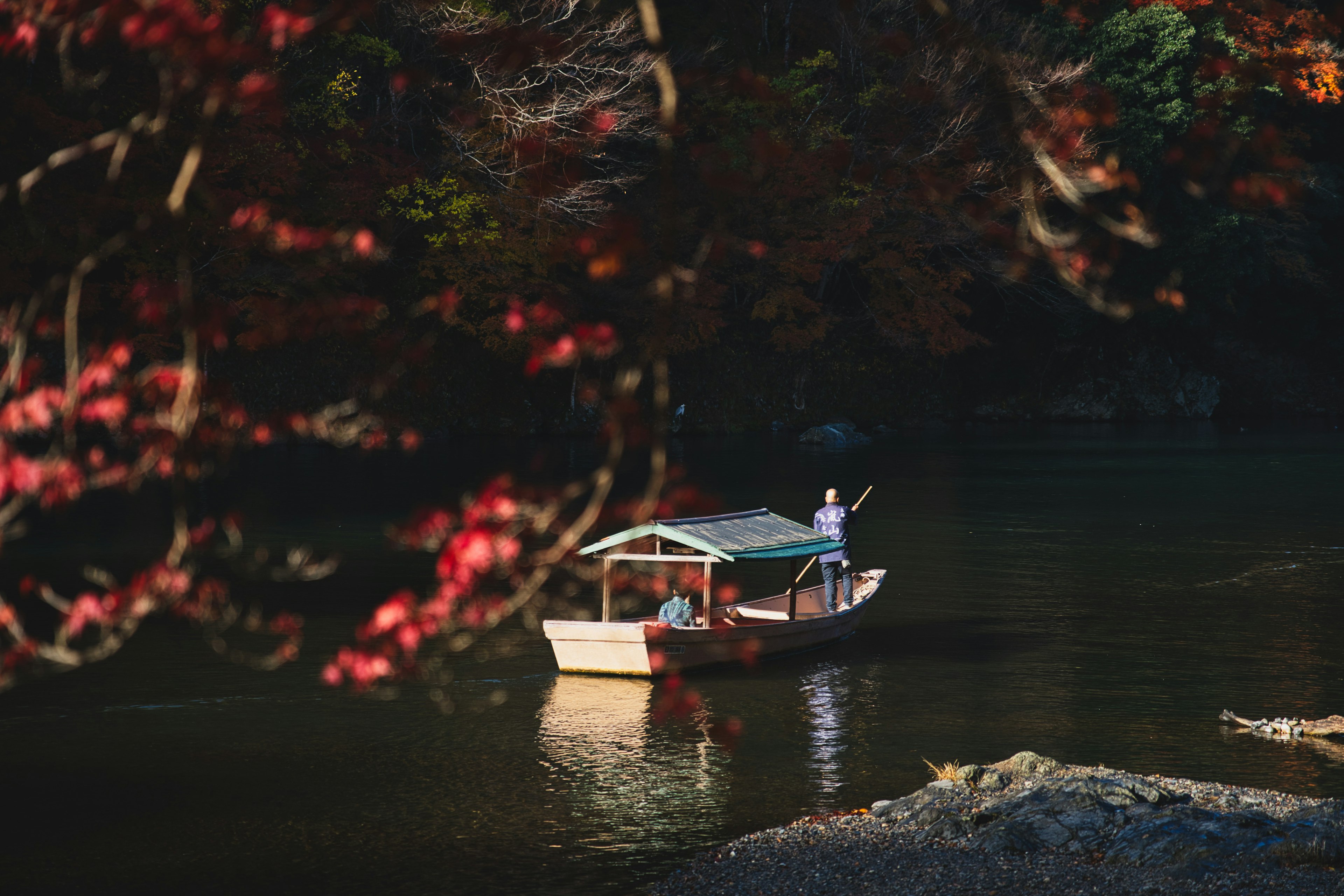 Small boat rowing on a river surrounded by autumn foliage