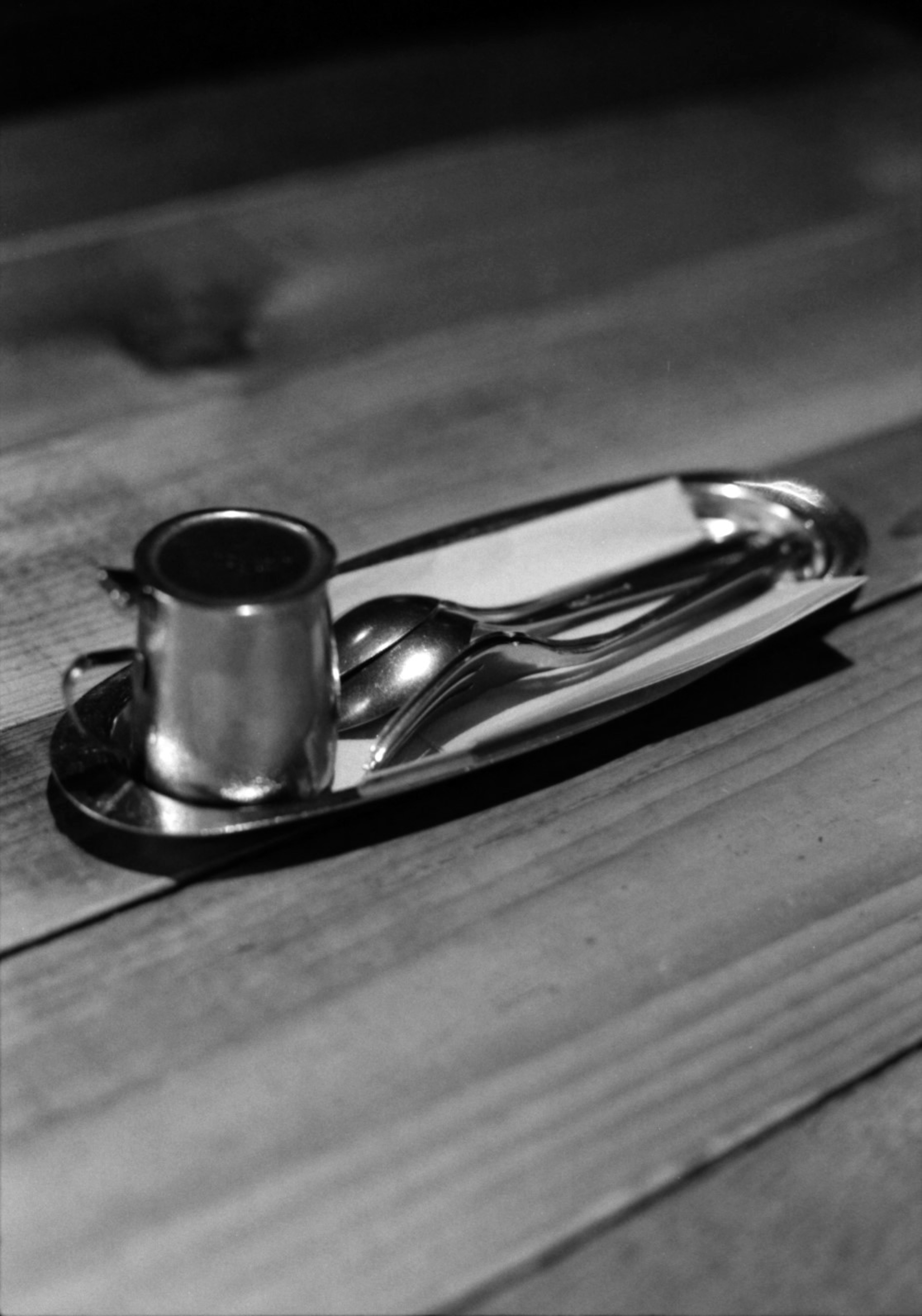 Silver candle holder and spoon placed on a wooden table