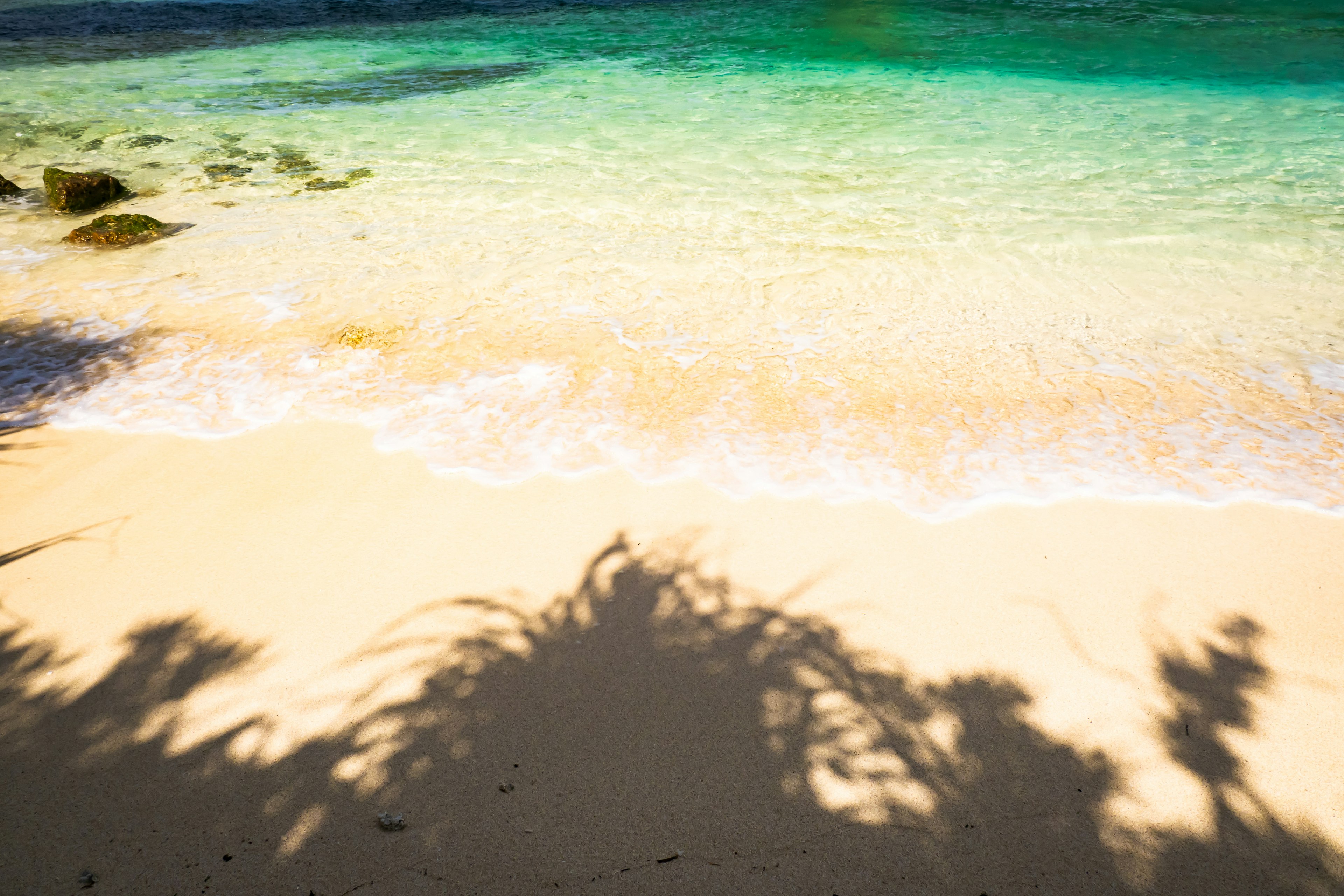 ทิวทัศน์ที่สวยงามของทะเลสีน้ำเงินและชายหาดทรายขาวที่มีเงาทอดบนทราย