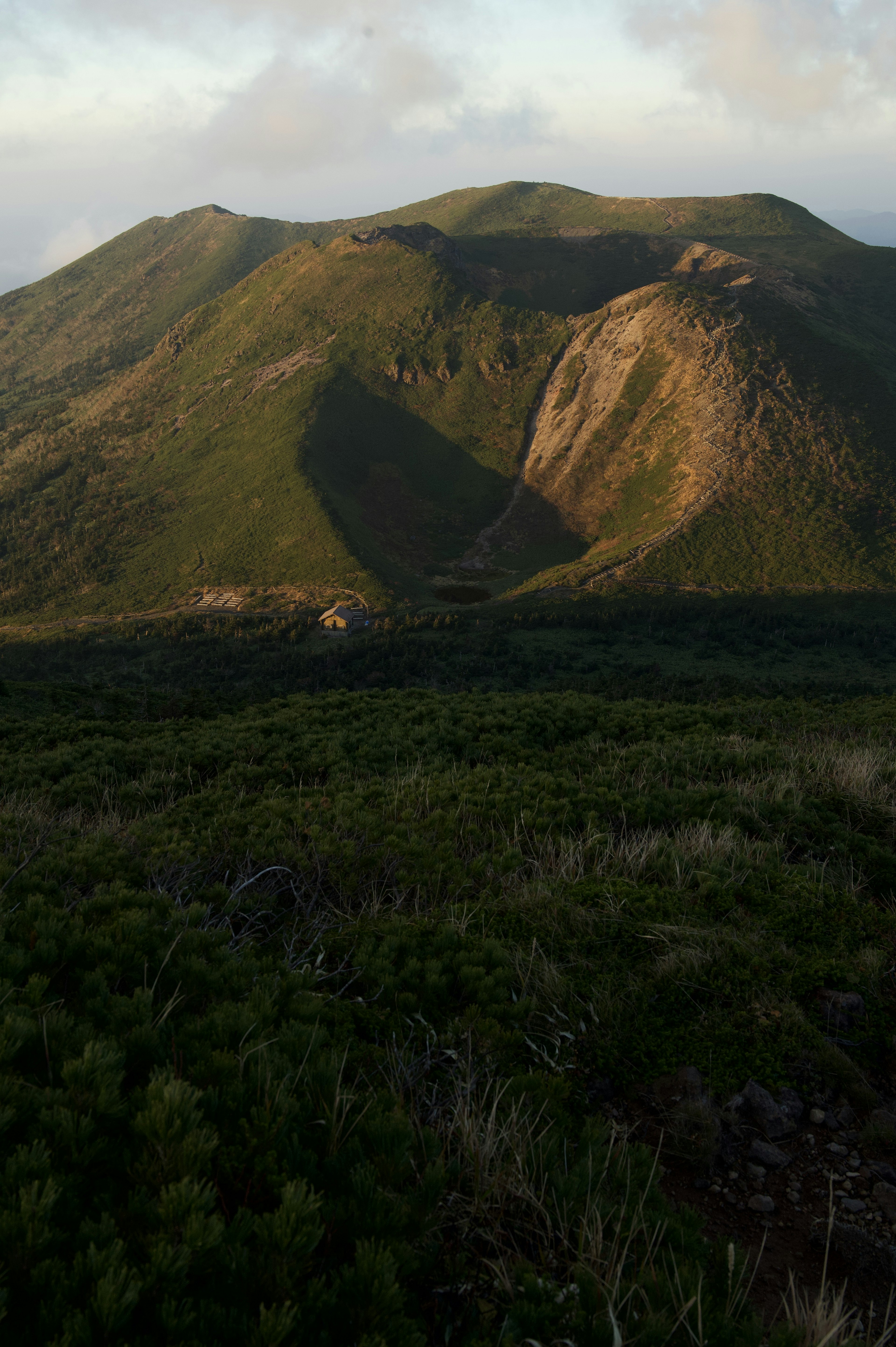 Vista panoramica di montagne verdi e pendii sotto una luce soffusa