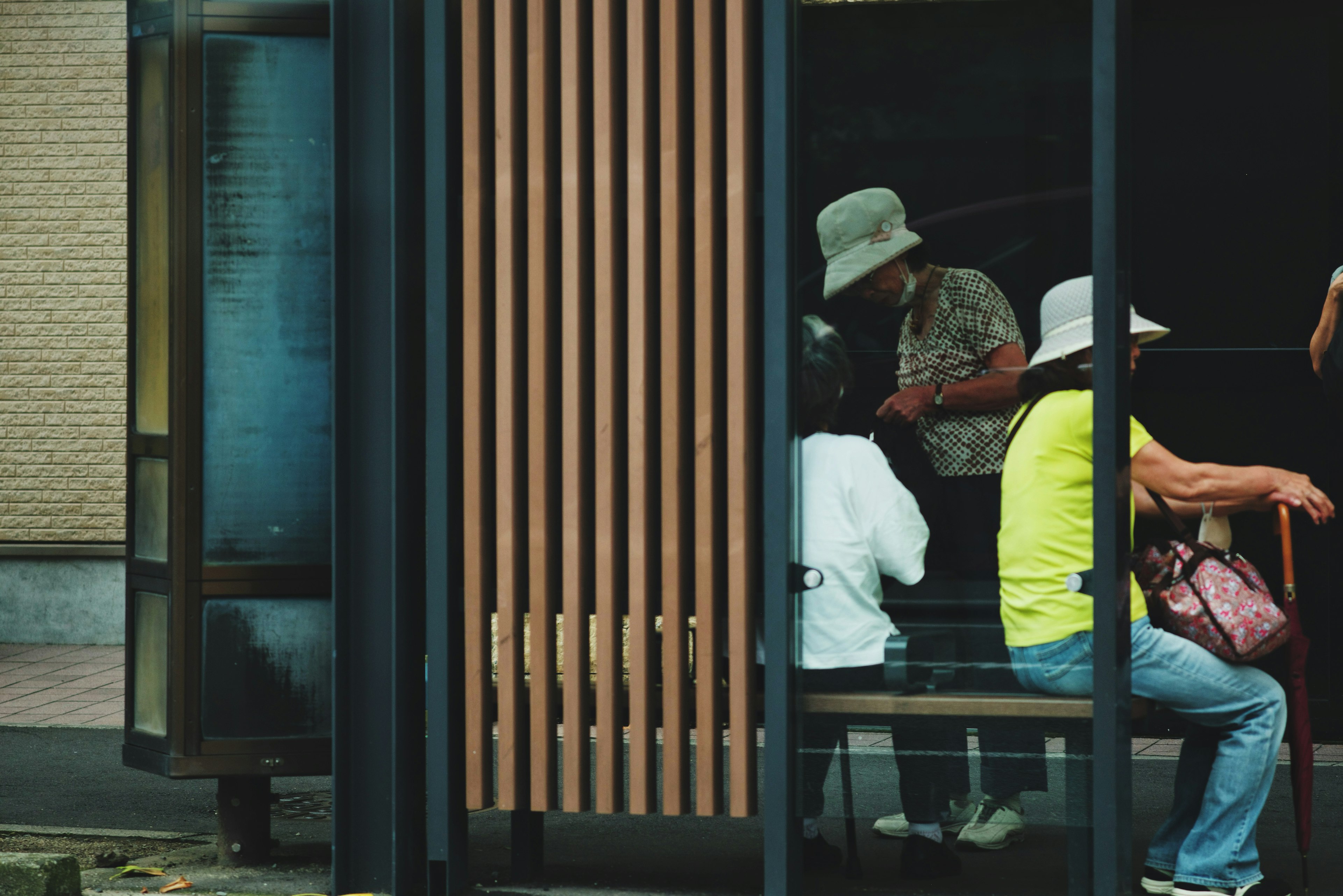 People waiting at a bus stop with wooden paneling