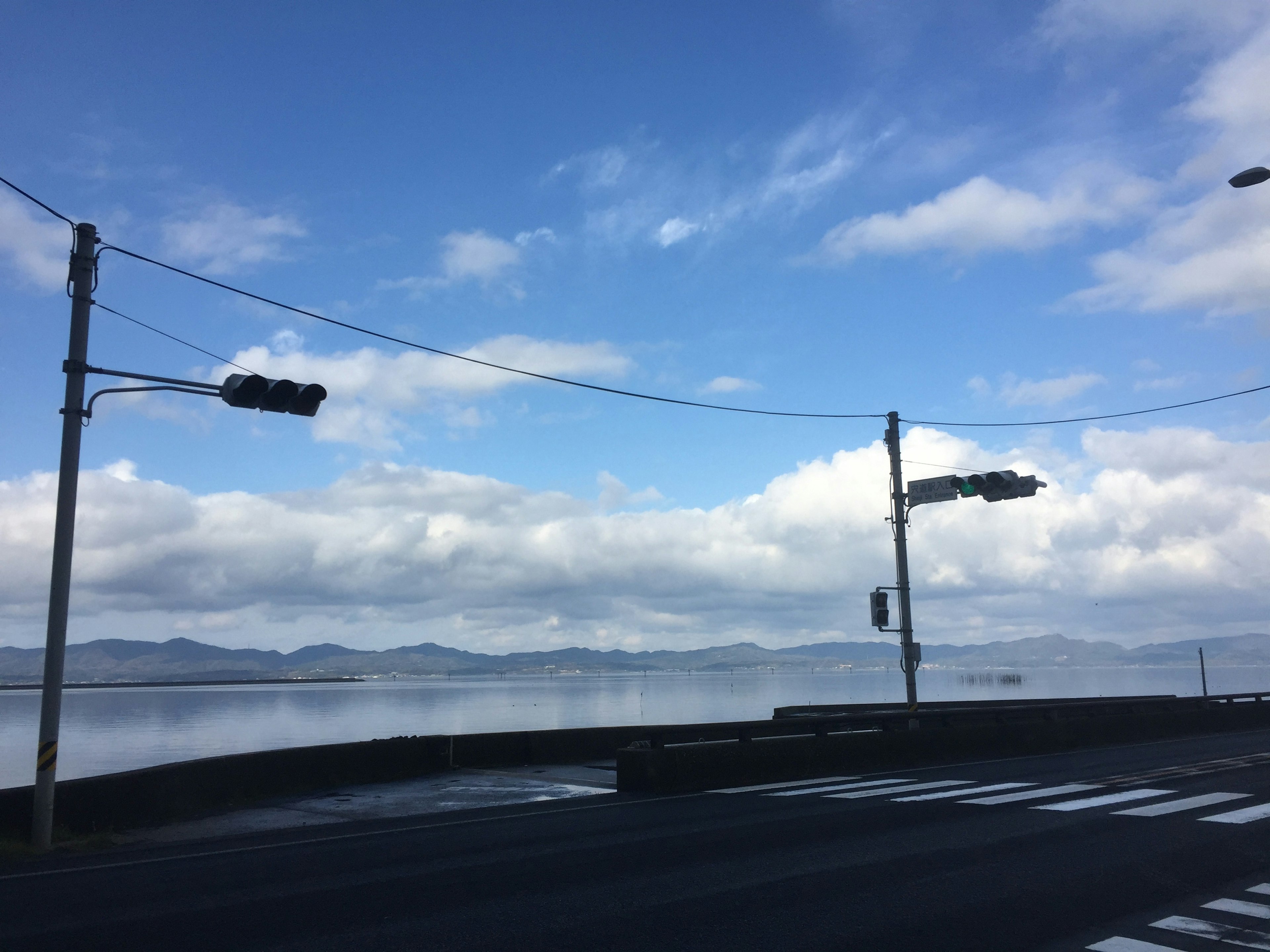 Scena costiera con cielo blu e nuvole che mostra semafori e lampioni