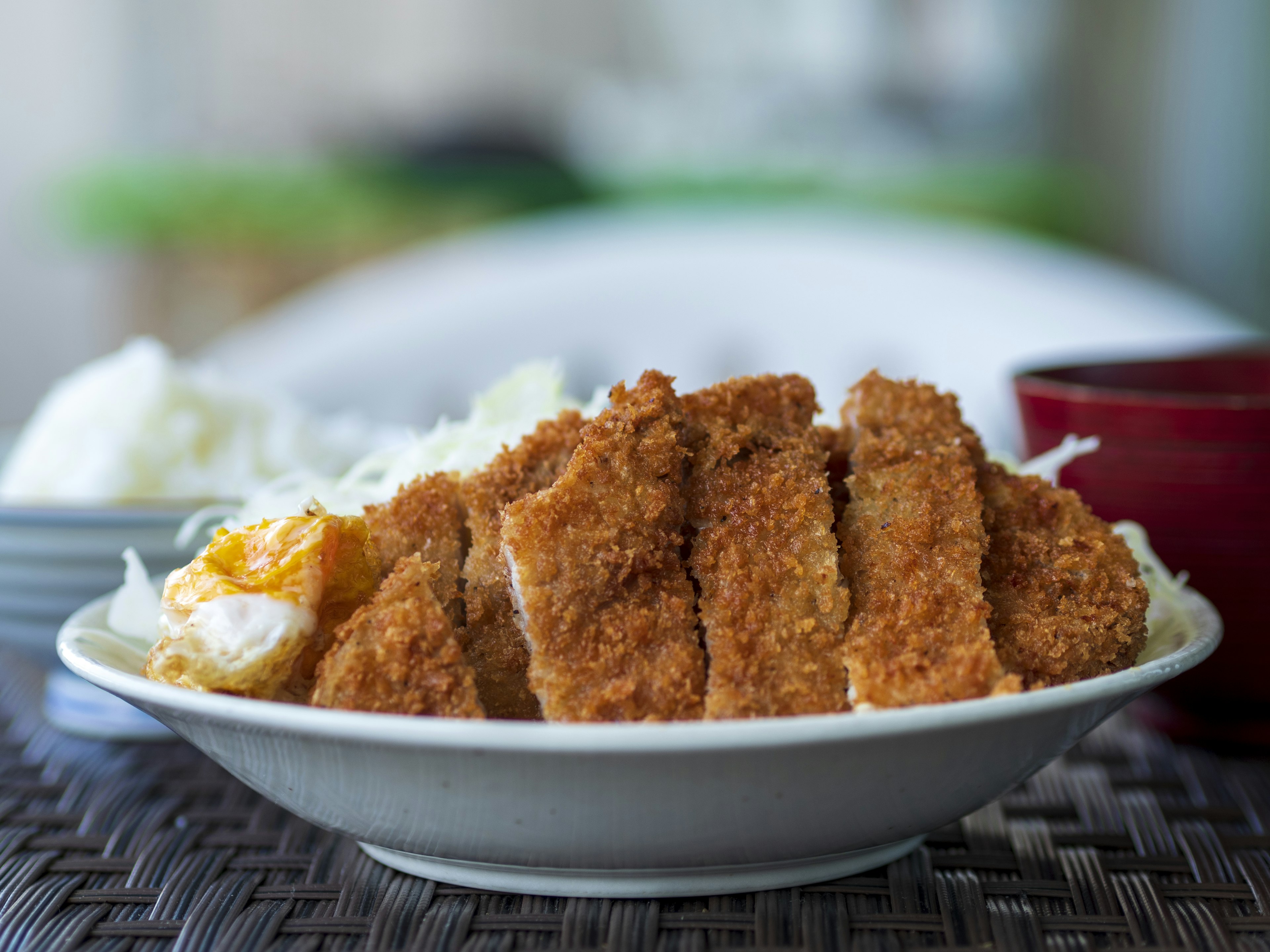 Plate of breaded pork cutlet served with rice and cabbage