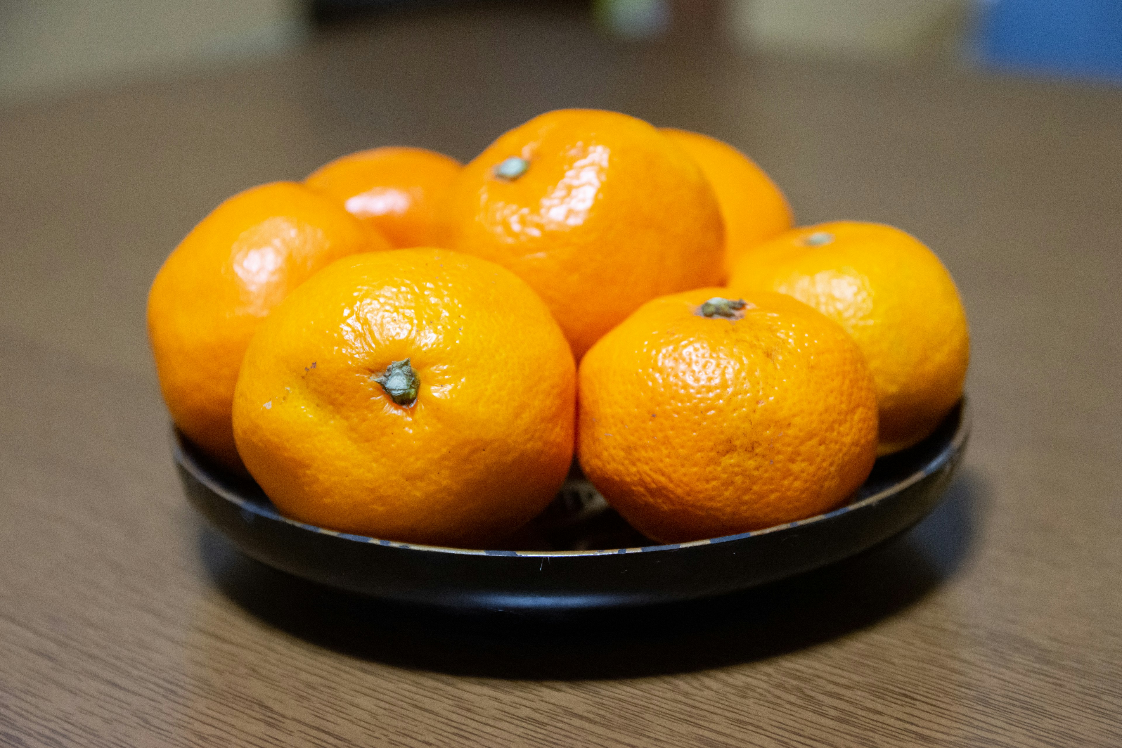 A round black plate holding several bright orange mandarins