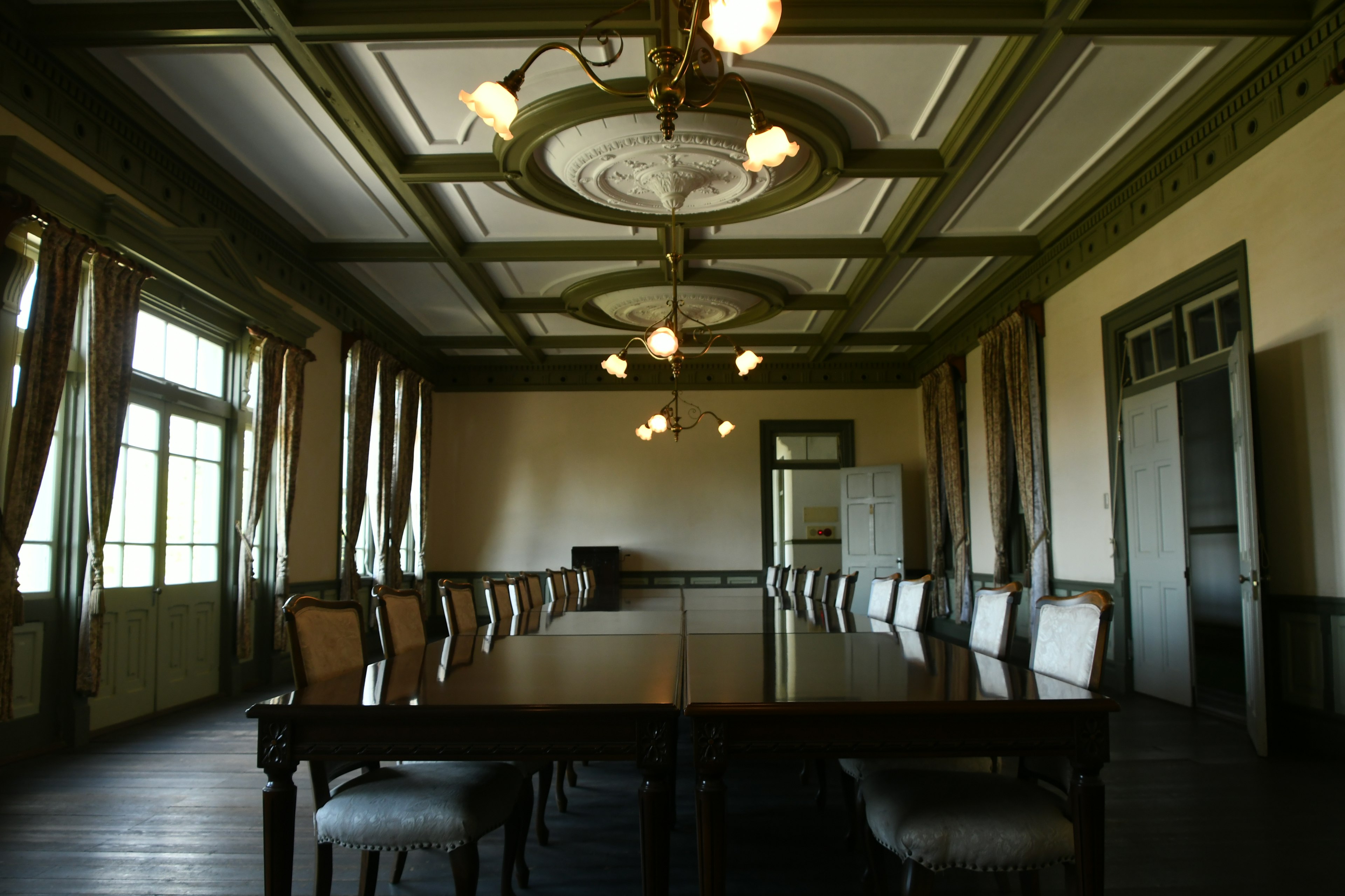 Interno di una sala conferenze spaziosa con un grande tavolo e sedie decorazioni del soffitto ornate e luce naturale dalle finestre