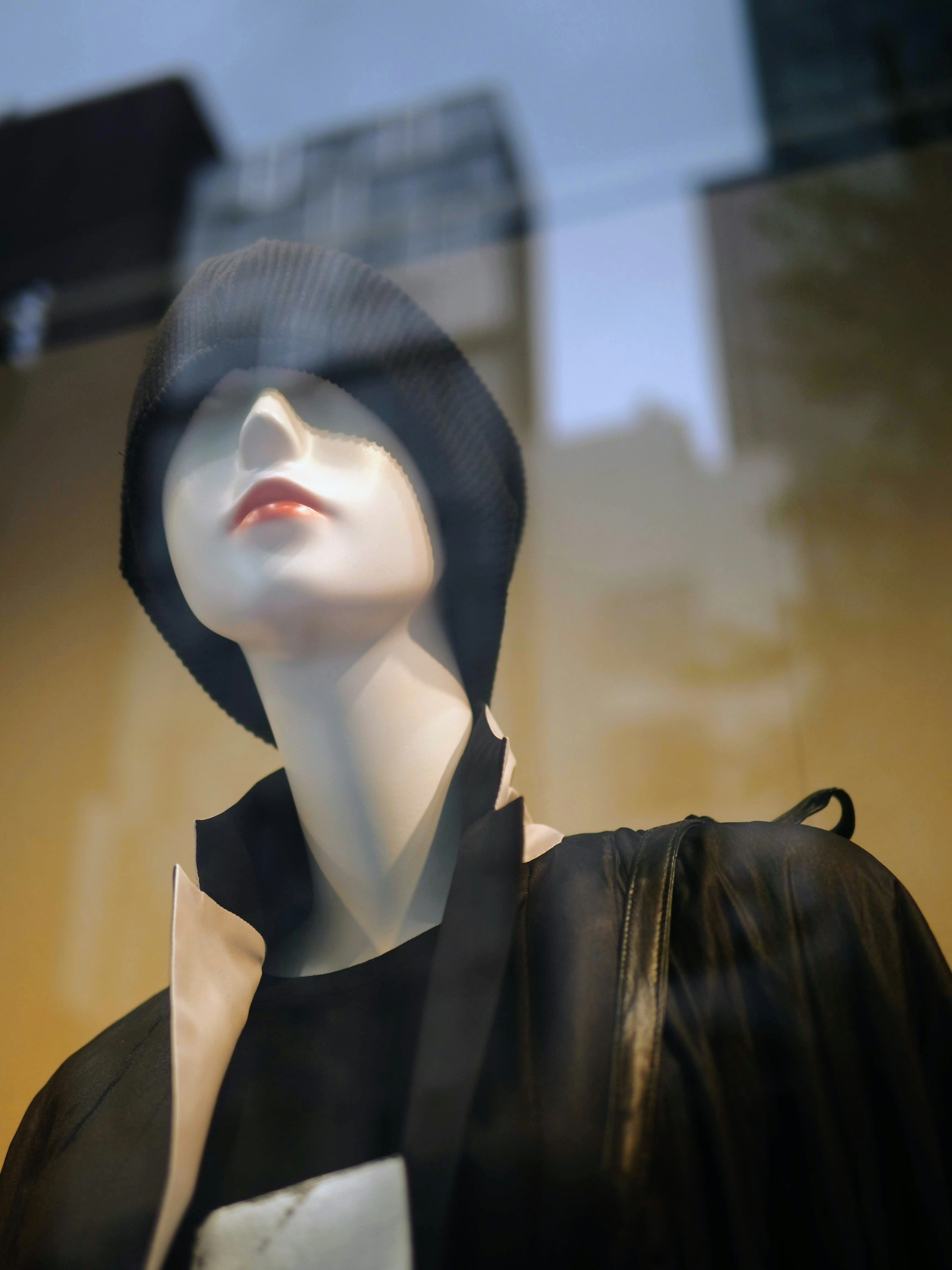 A mannequin in a window display wearing a black hat and red lipstick