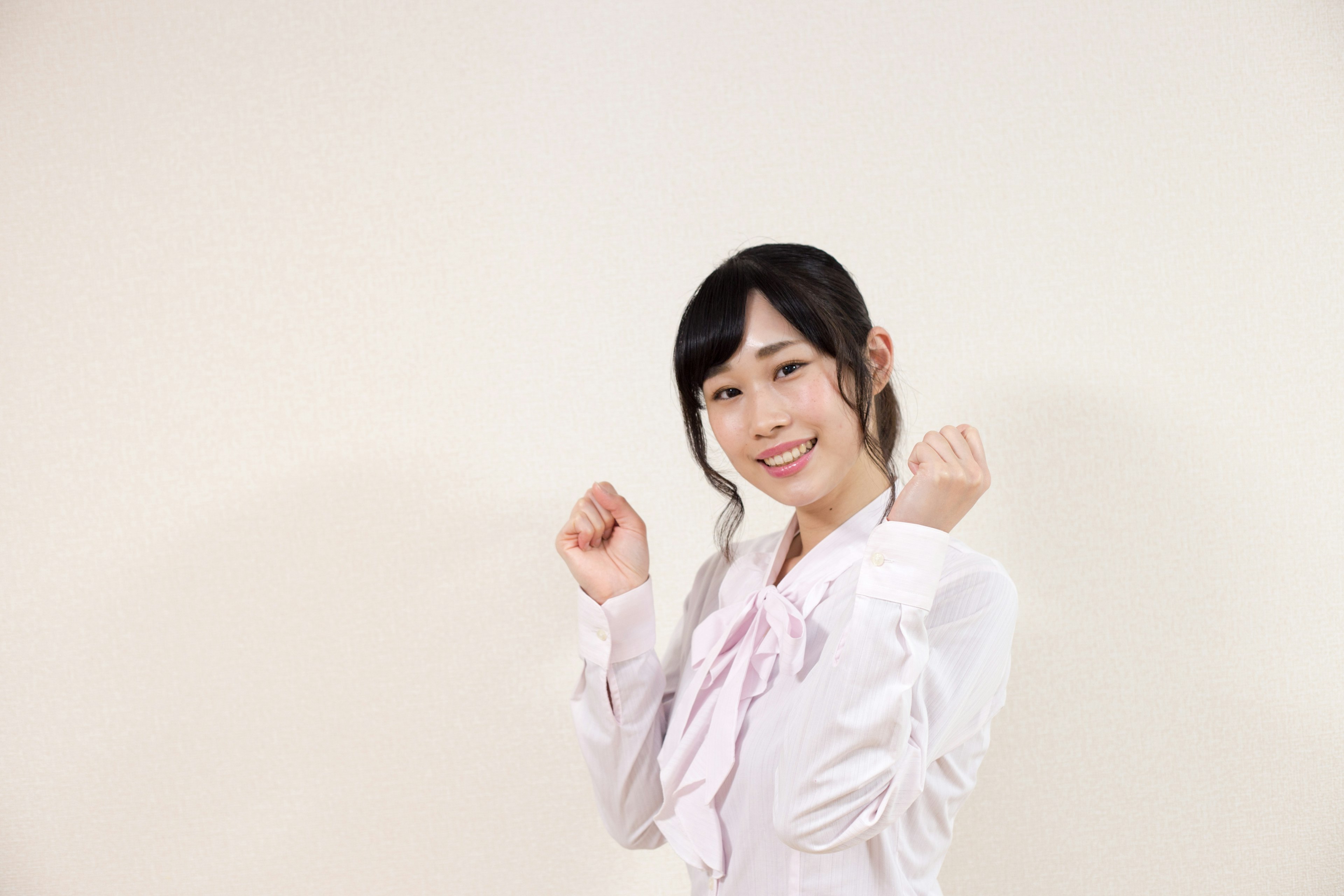 A woman in a white shirt smiling with her fists raised