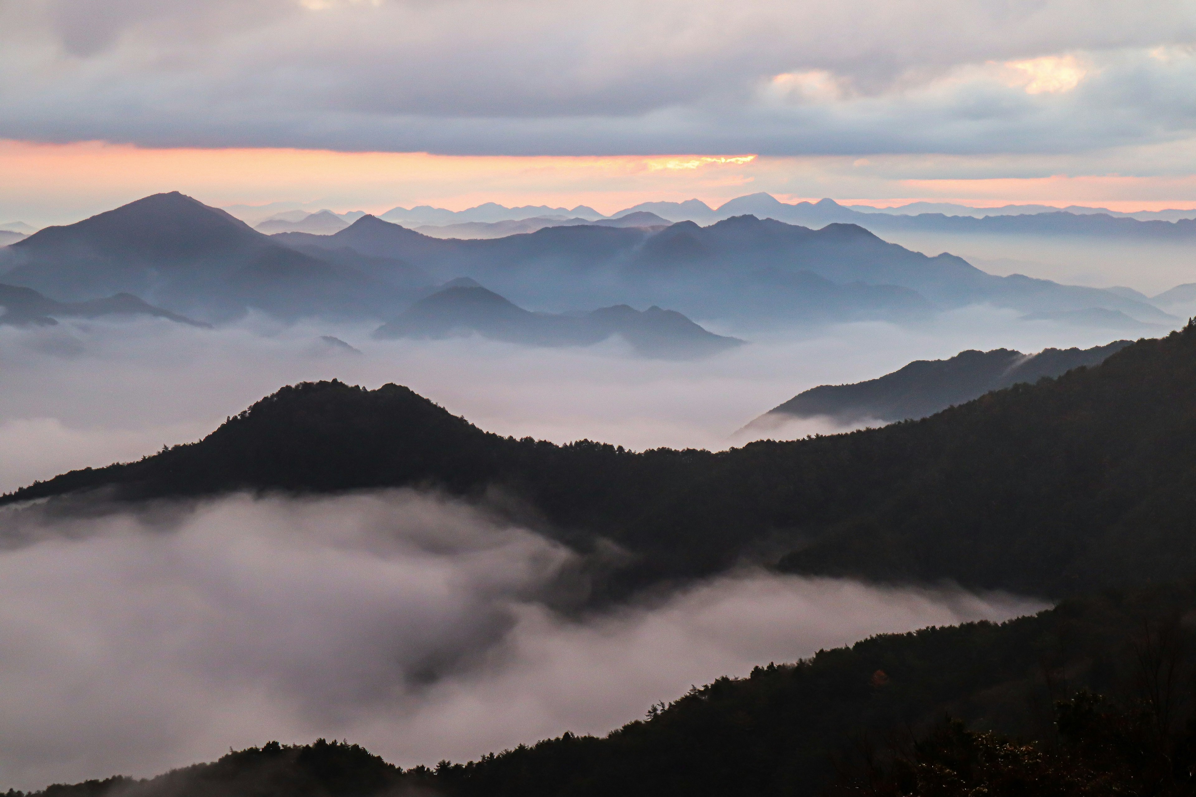 Vista panoramica di montagne avvolte nella nebbia all'alba